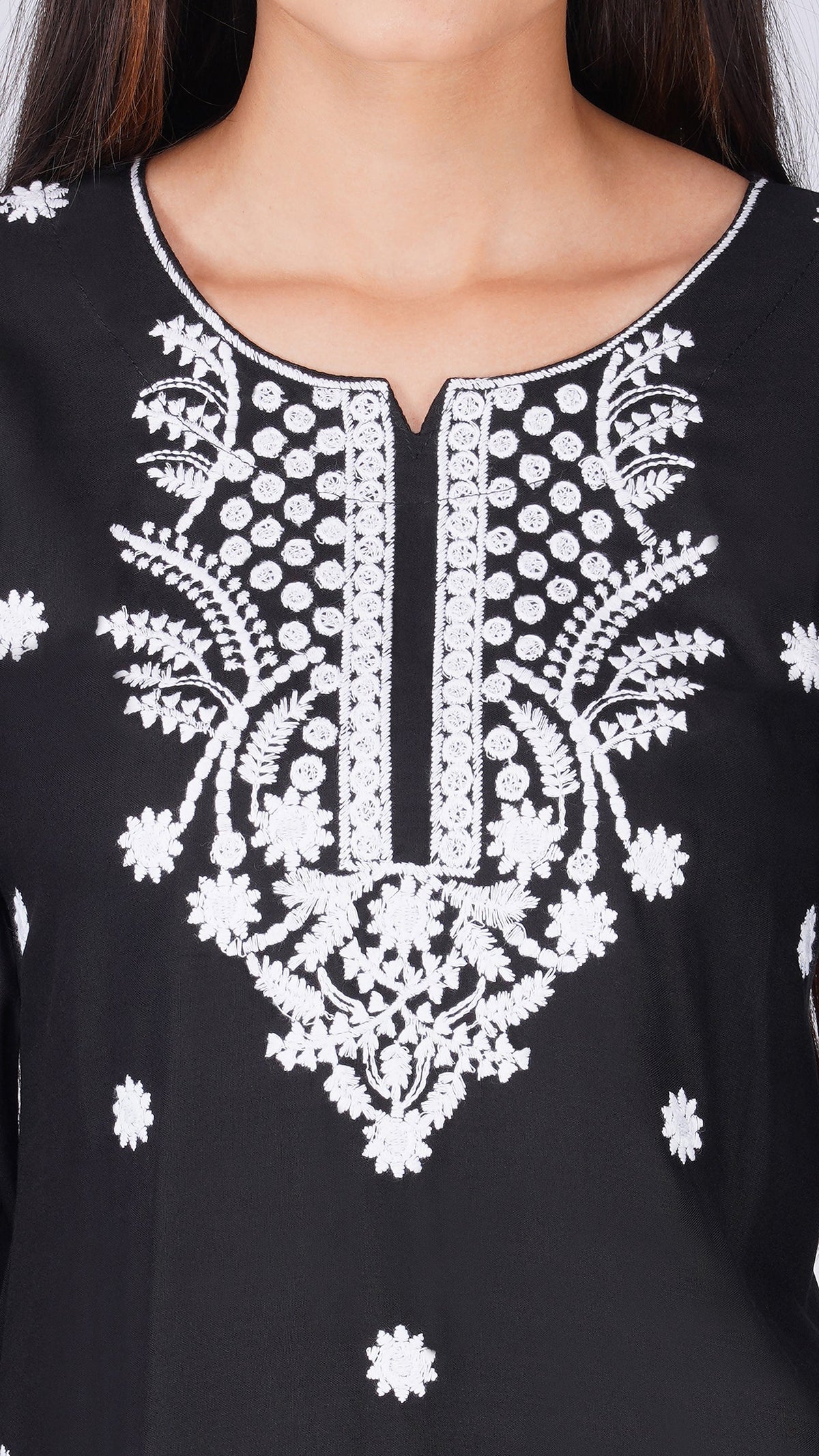 Close-up of a black tunic top with intricate white floral embroidery around the neckline and scattered embroidered motifs on the fabric.