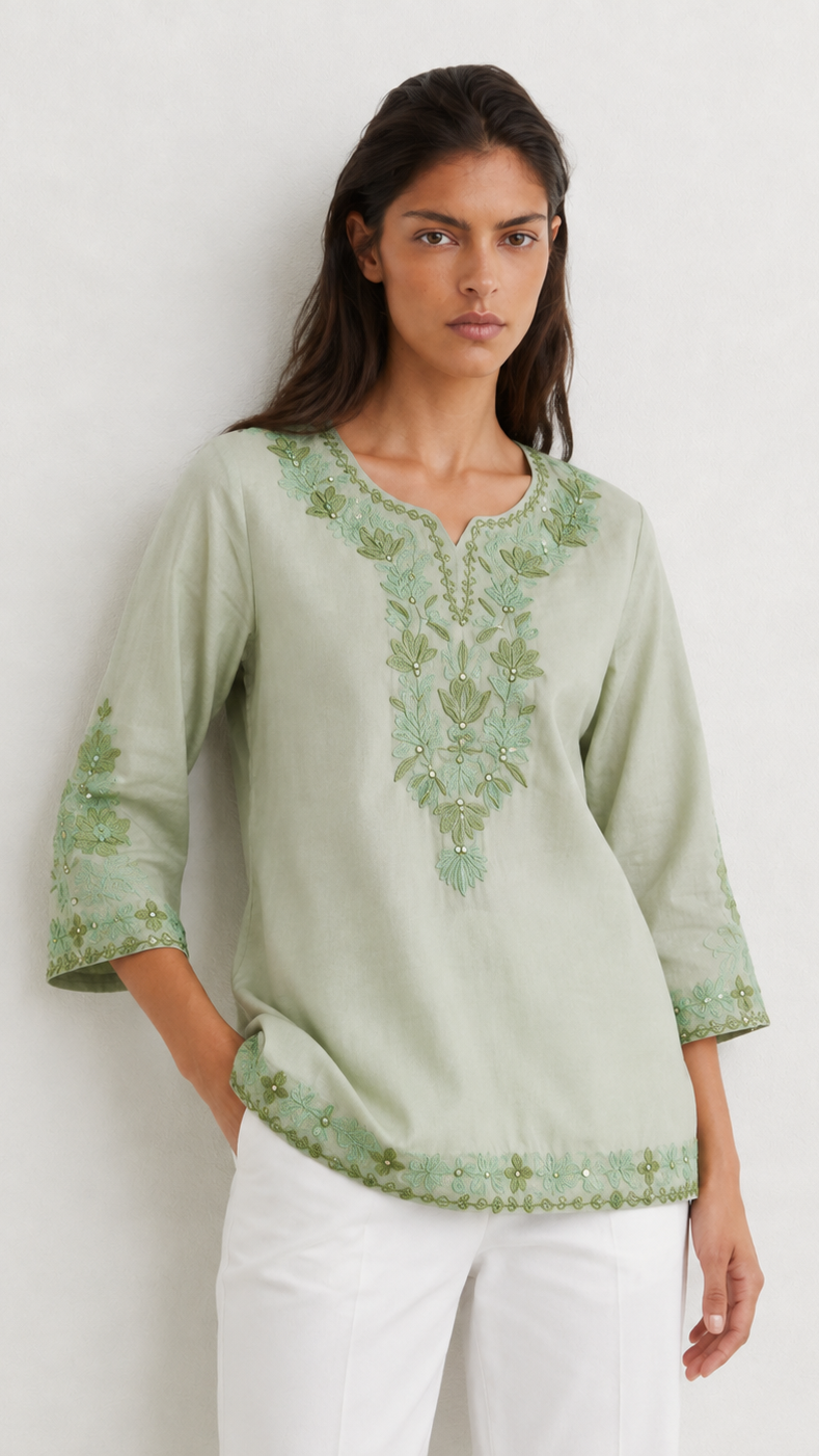 Young woman wearing a sage green embroidered kurta top with tonal floral threadwork, three-quarter sleeves and white trousers.