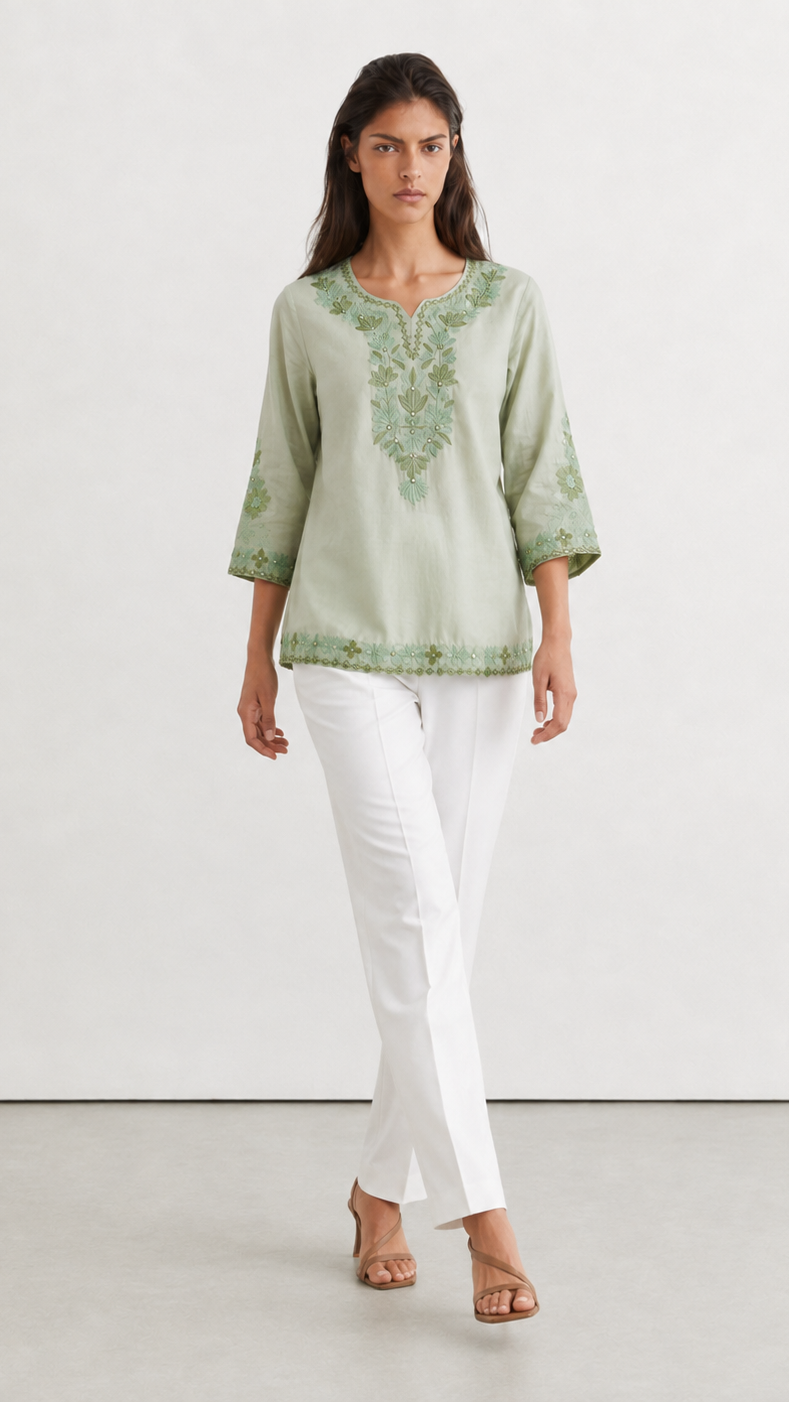 Young woman wearing a sage green embroidered kurta top with tonal floral threadwork, three-quarter sleeves and white trousers.
