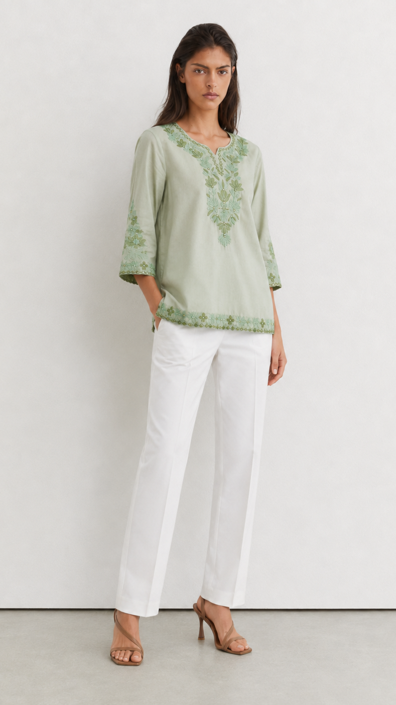 Young woman wearing a sage green embroidered kurta top with tonal floral threadwork, three-quarter sleeves and white trousers.