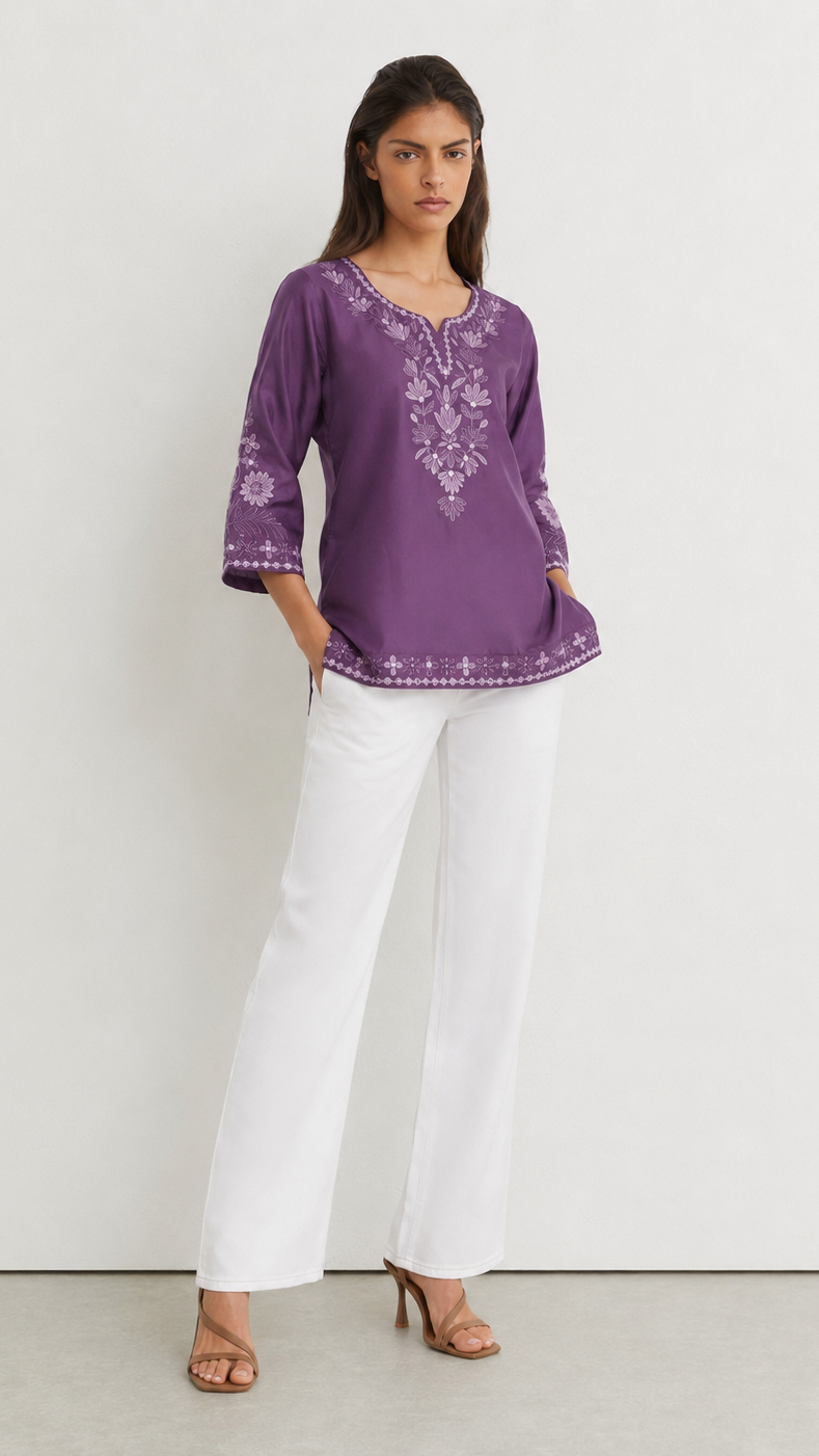 Young woman wearing a purple embroidered kurta top with tonal floral threadwork, three-quarter sleeves and white trousers.