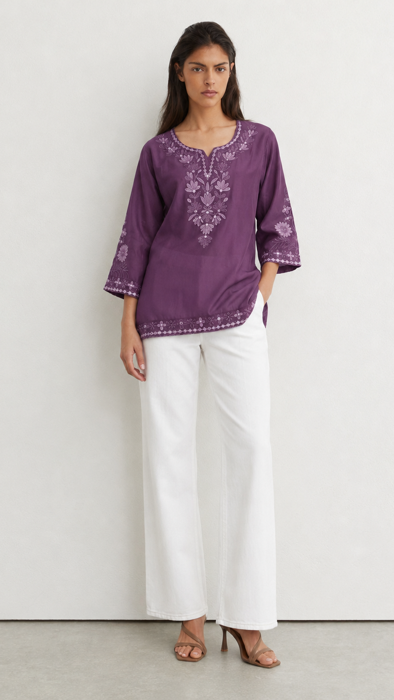 Young woman wearing a purple embroidered kurta top with tonal floral threadwork, three-quarter sleeves and white trousers.