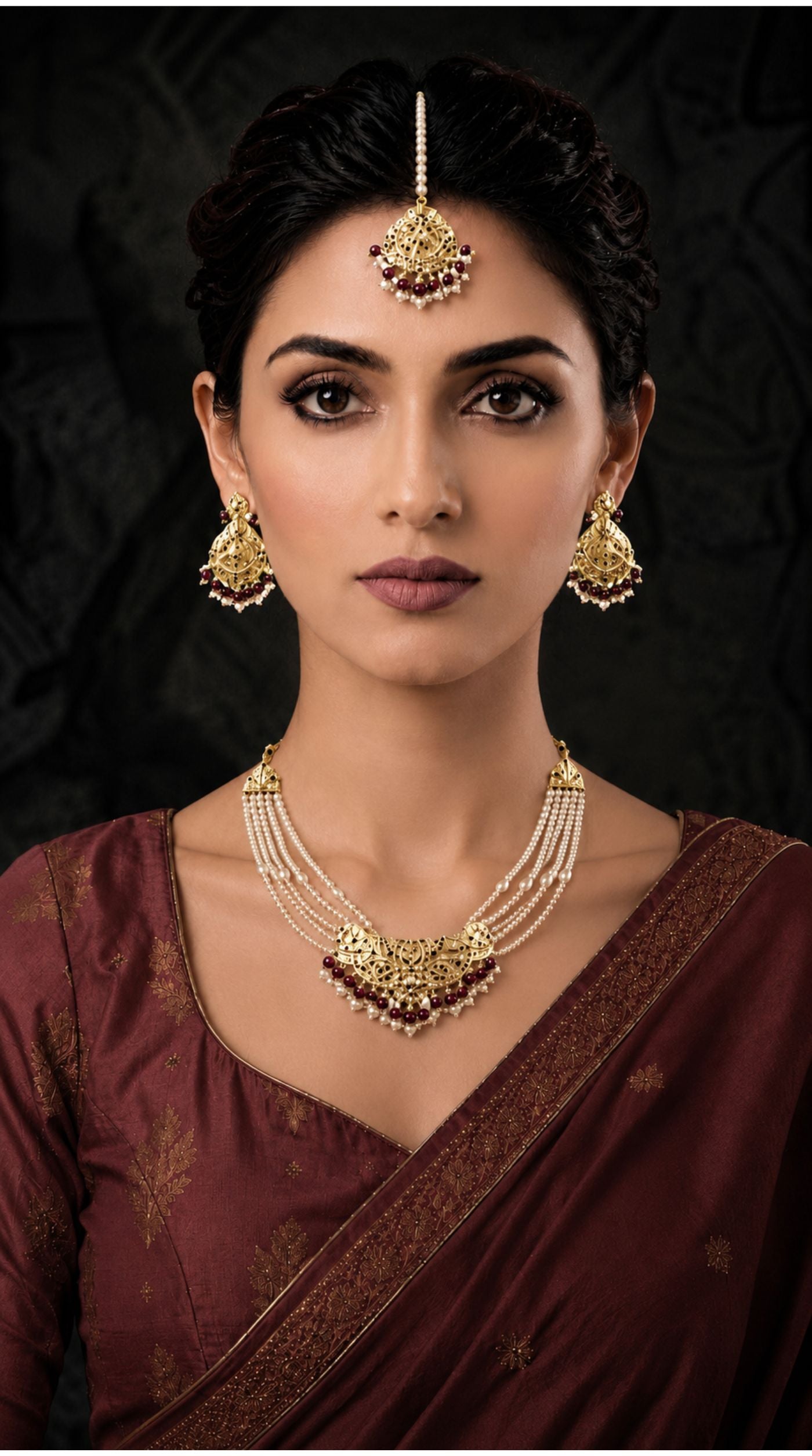Gold pearl and Maroon Jadau necklace set with layered pearl strands, matching earrings, and maang tikka featuring intricate filigree work and green bead detailing