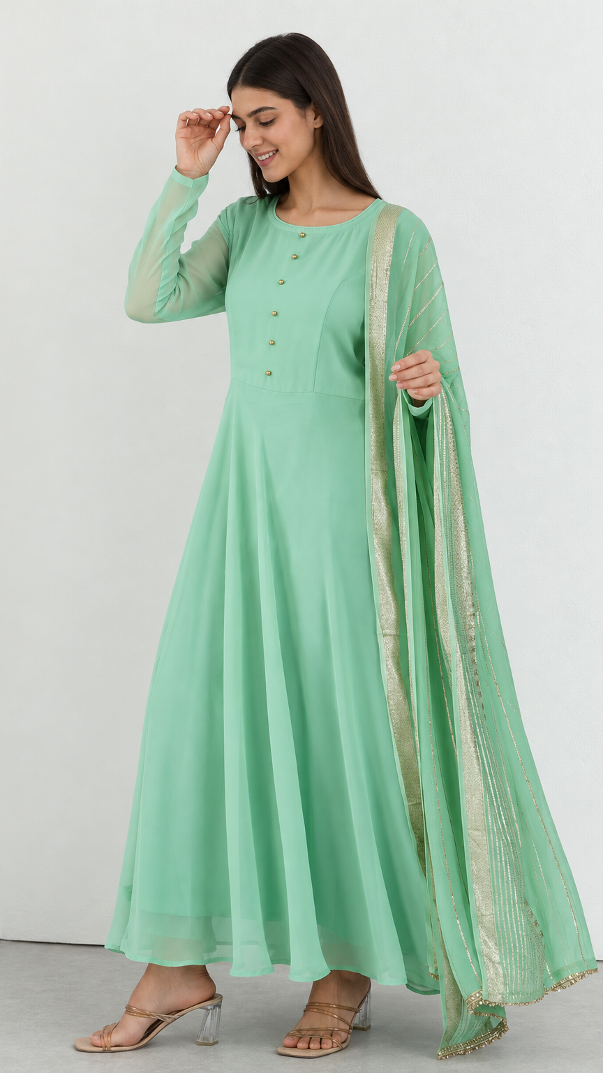 A woman modeling a mint green long kurta with a matching sheer dupatta featuring gold border detailing, set against a plain white studio background.