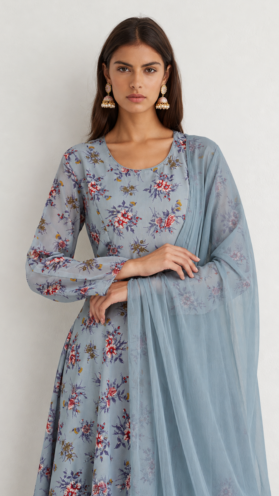 A woman modeling a light blue floral printed kurta with long sleeves and a matching sheer dupatta, set against a plain light gray background.