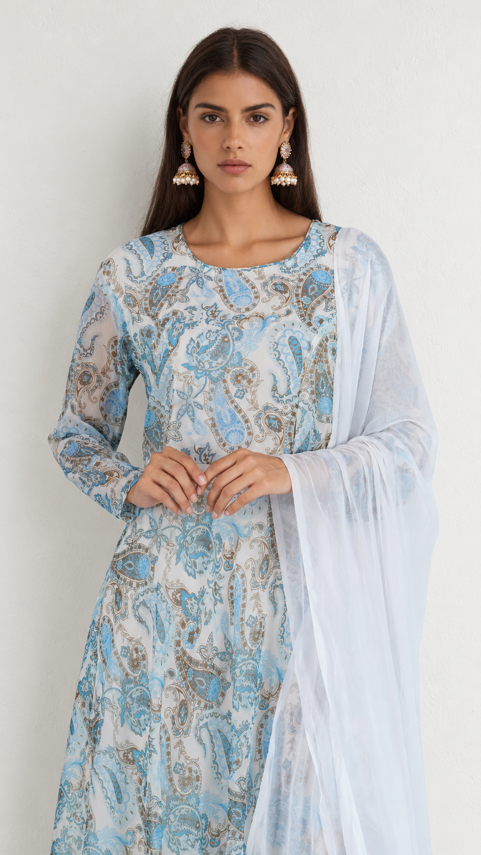 A woman modeling a light blue and white printed traditional kurta set with a matching sheer dupatta, featuring intricate paisley patterns.