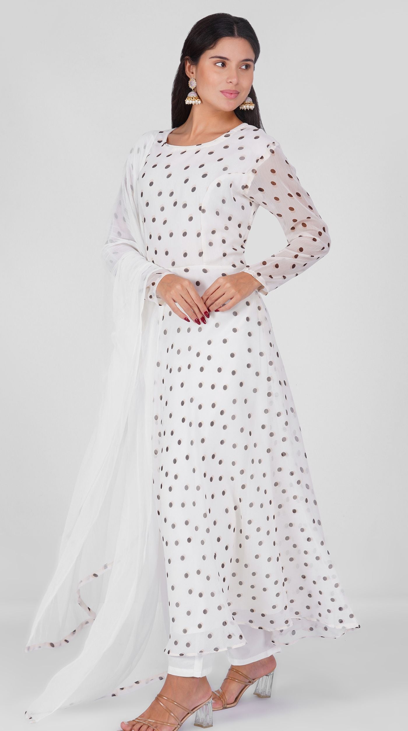 Woman wearing a white georgette bias cut suit set with black polka dot print, white crepe trousers, and printed chiffon dupatta – Diya Online