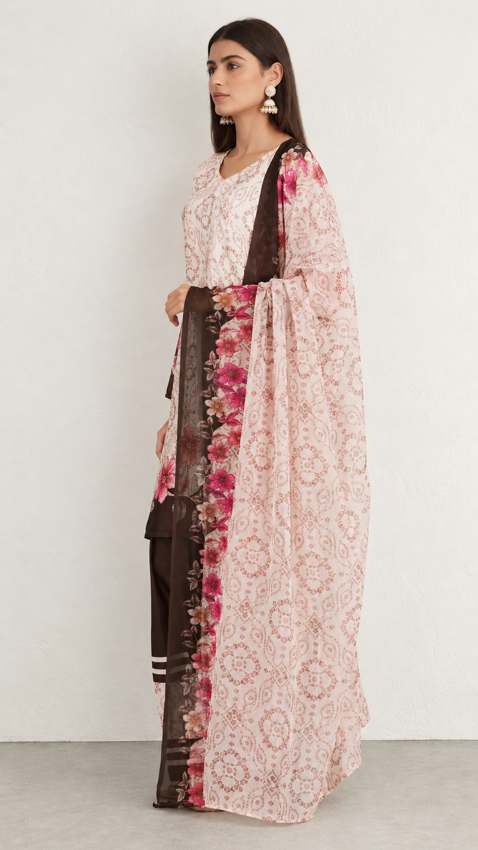 A woman models a traditional Indian outfit consisting of a light pink printed kurta, a dark brown border, and a matching pink printed dupatta, set against a plain light gray studio background.