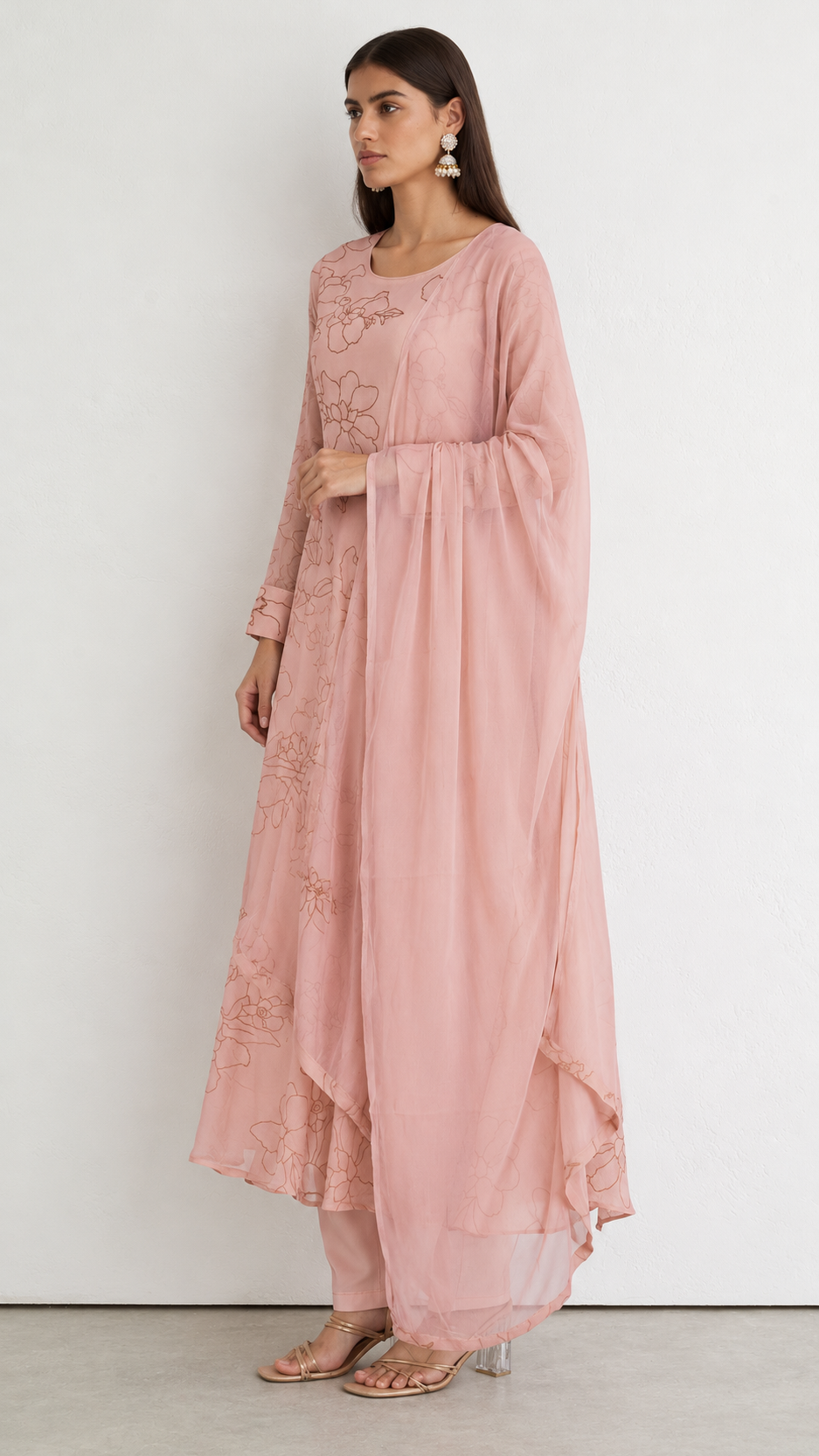 A woman modeling a dusty pink traditional outfit with a long-sleeved embroidered kurta and a matching sheer draped overlay, set against a plain white studio background.
