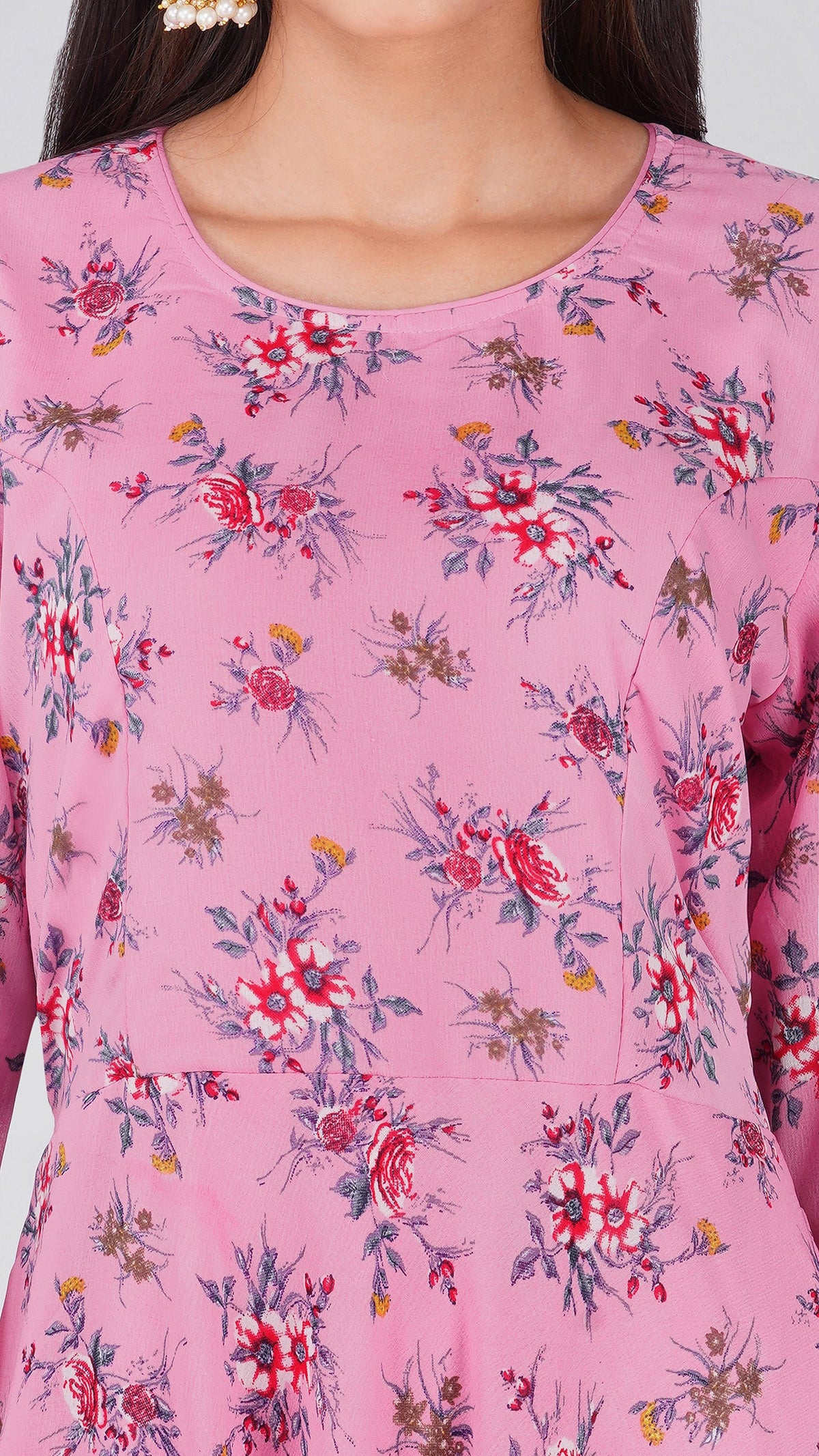 A close-up of a pink long-sleeve top or dress featuring a delicate red, white, and blue floral print, worn by a model.
