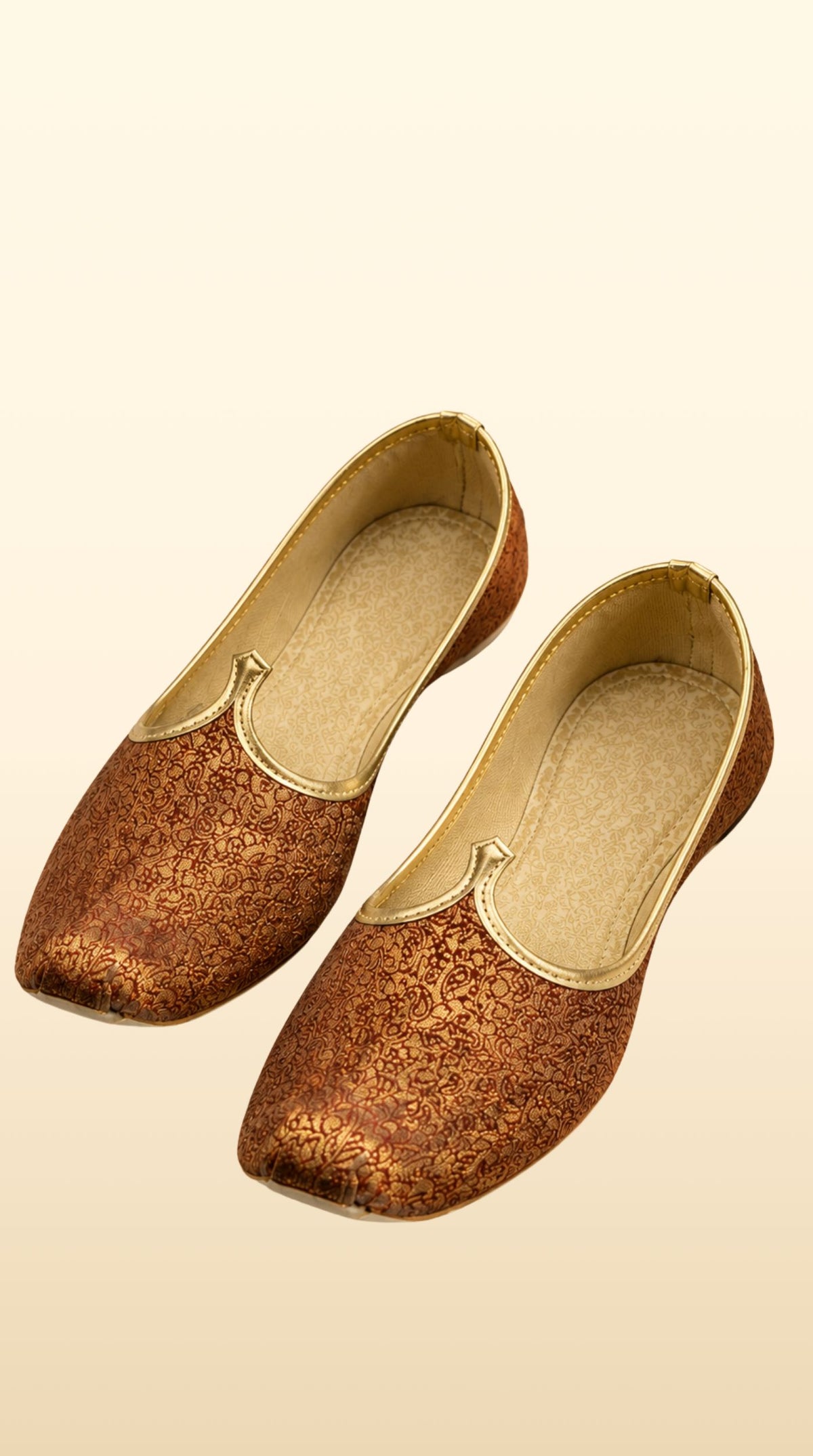 A pair of metallic bronze traditional Indian shoes with gold trim, displayed on a light beige background.