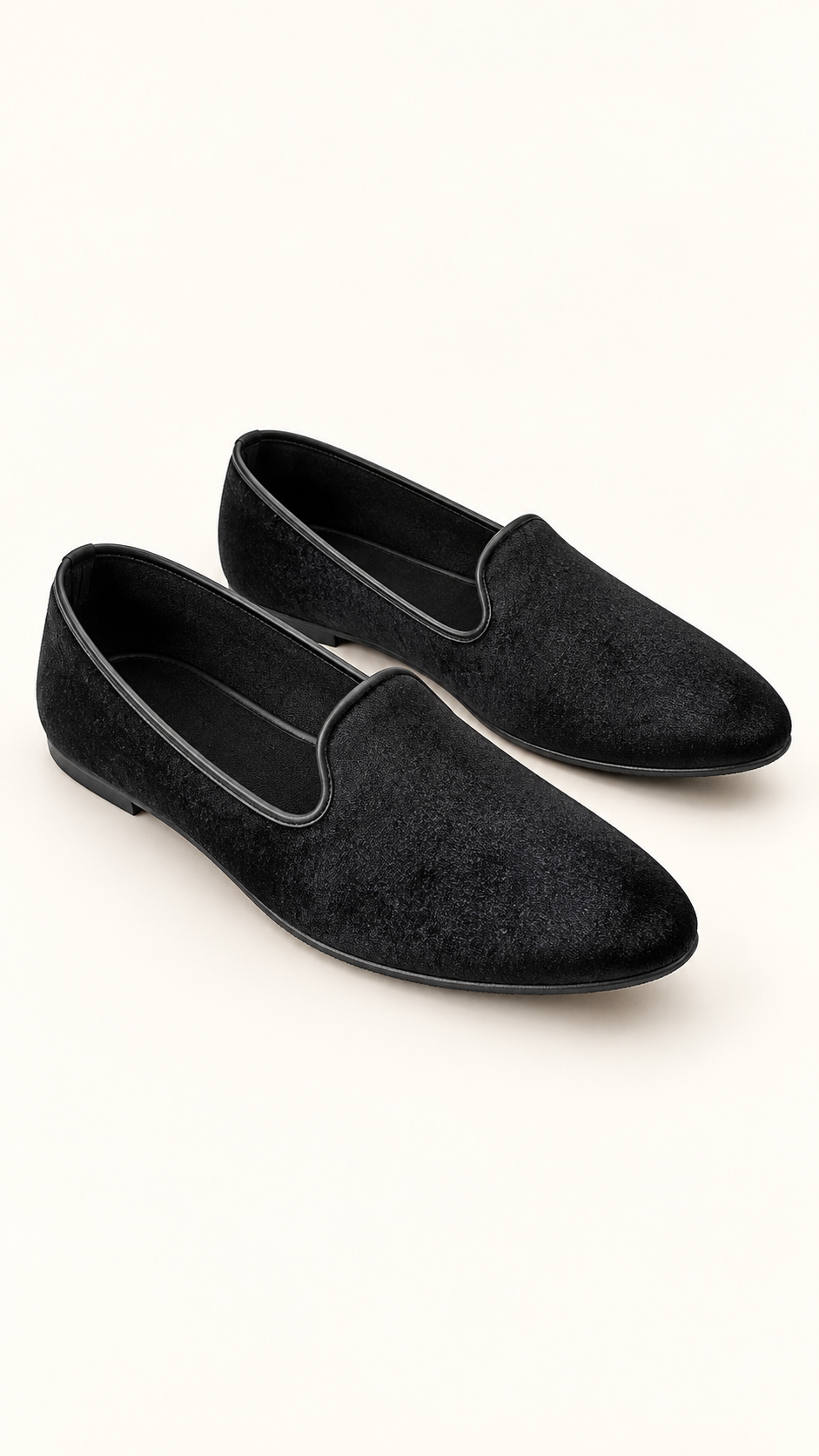 A pair of black velvet slip-on loafers with a low block heel, displayed on a clean off-white background.