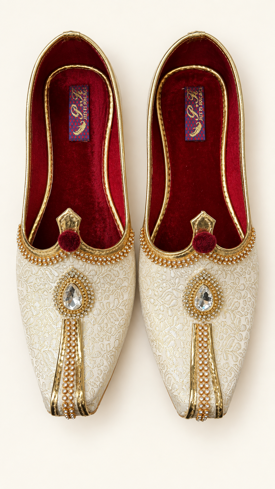 A pair of traditional Indian groom's shoes (Mithai) in off-white brocade fabric with gold embroidery, gold beadwork, and a red velvet insole.
