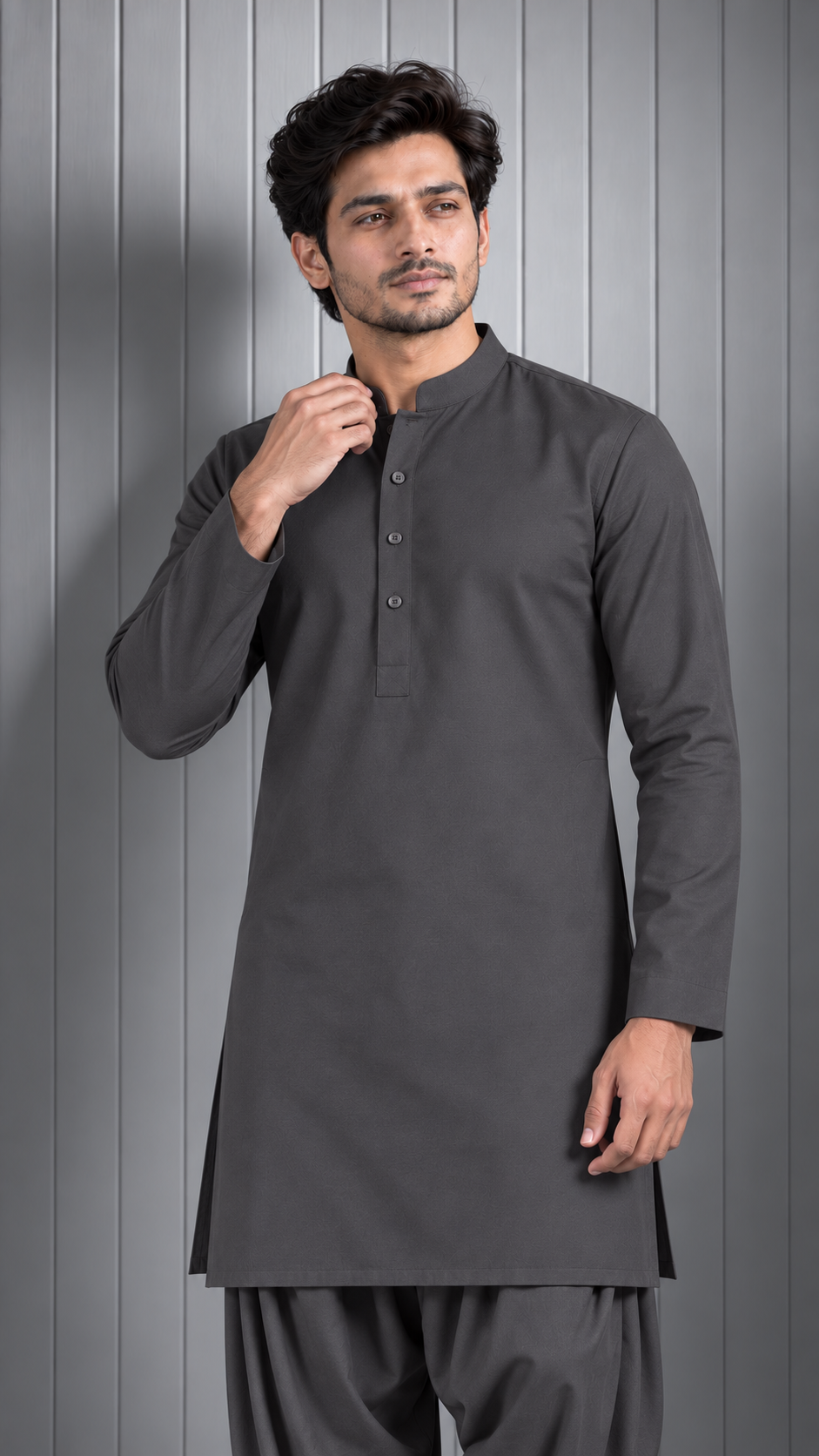 A man modeling a dark gray long-sleeve kurta with a mandarin collar and three-button placket, paired with matching dark gray trousers, set against a gray paneled background.