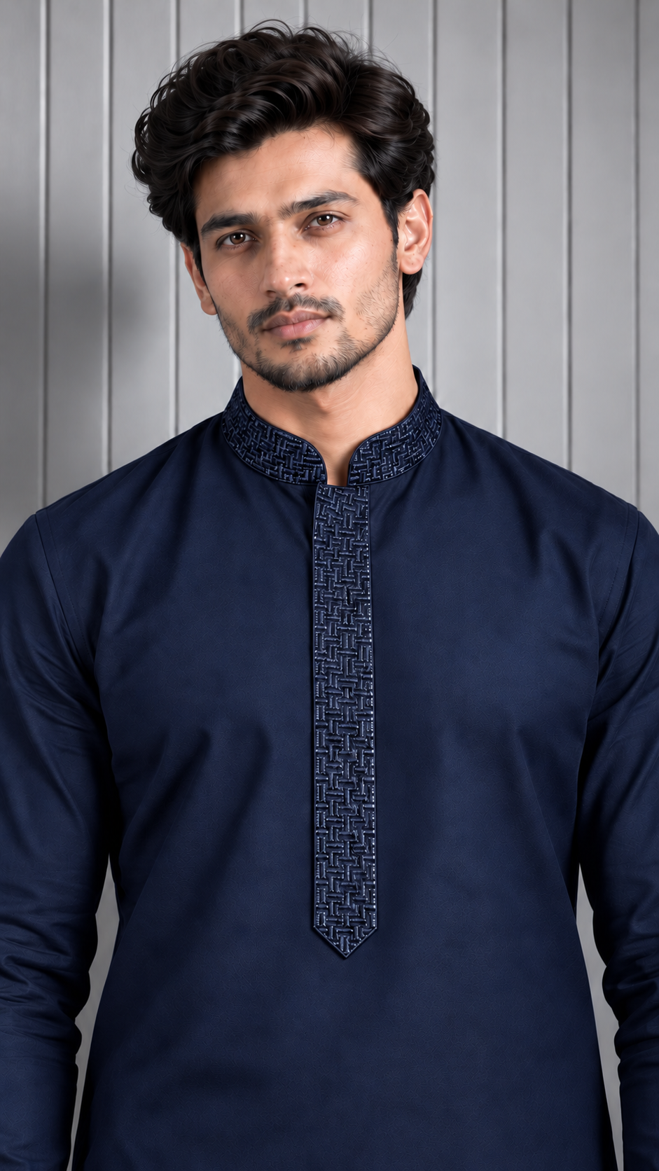 A man wearing a navy blue long-sleeve kurta with a textured geometric pattern on the placket and collar, set against a gray paneled background.