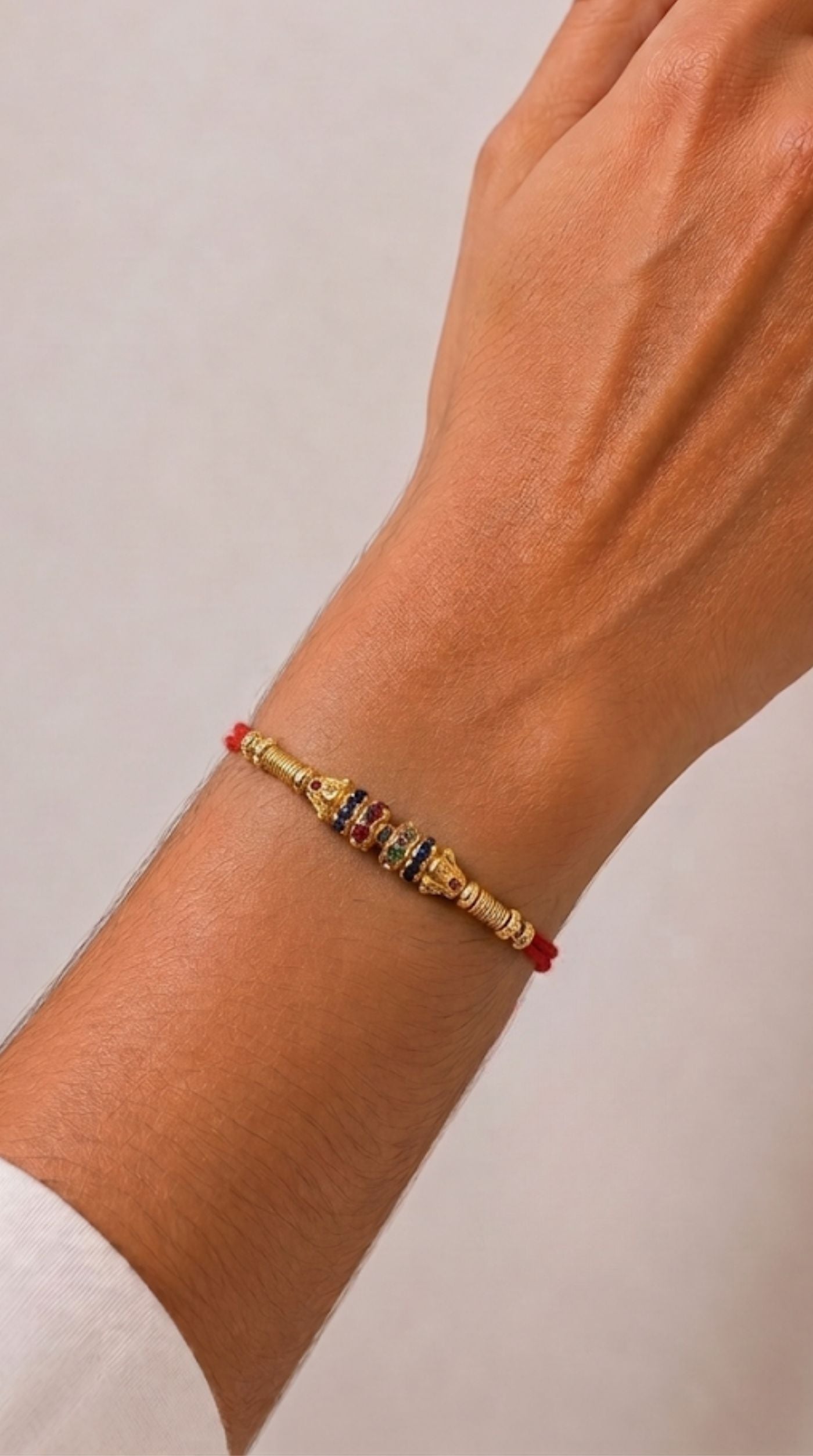 Single beaded maroon Rakhi with gold and green bead accents