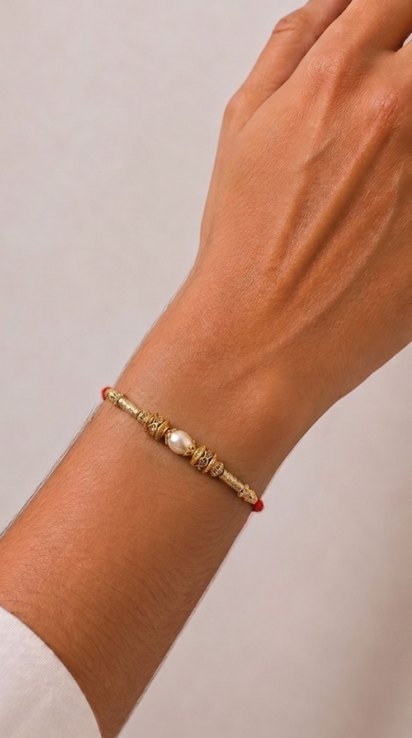 Light gold Rakhi with pearl centre and antique finish