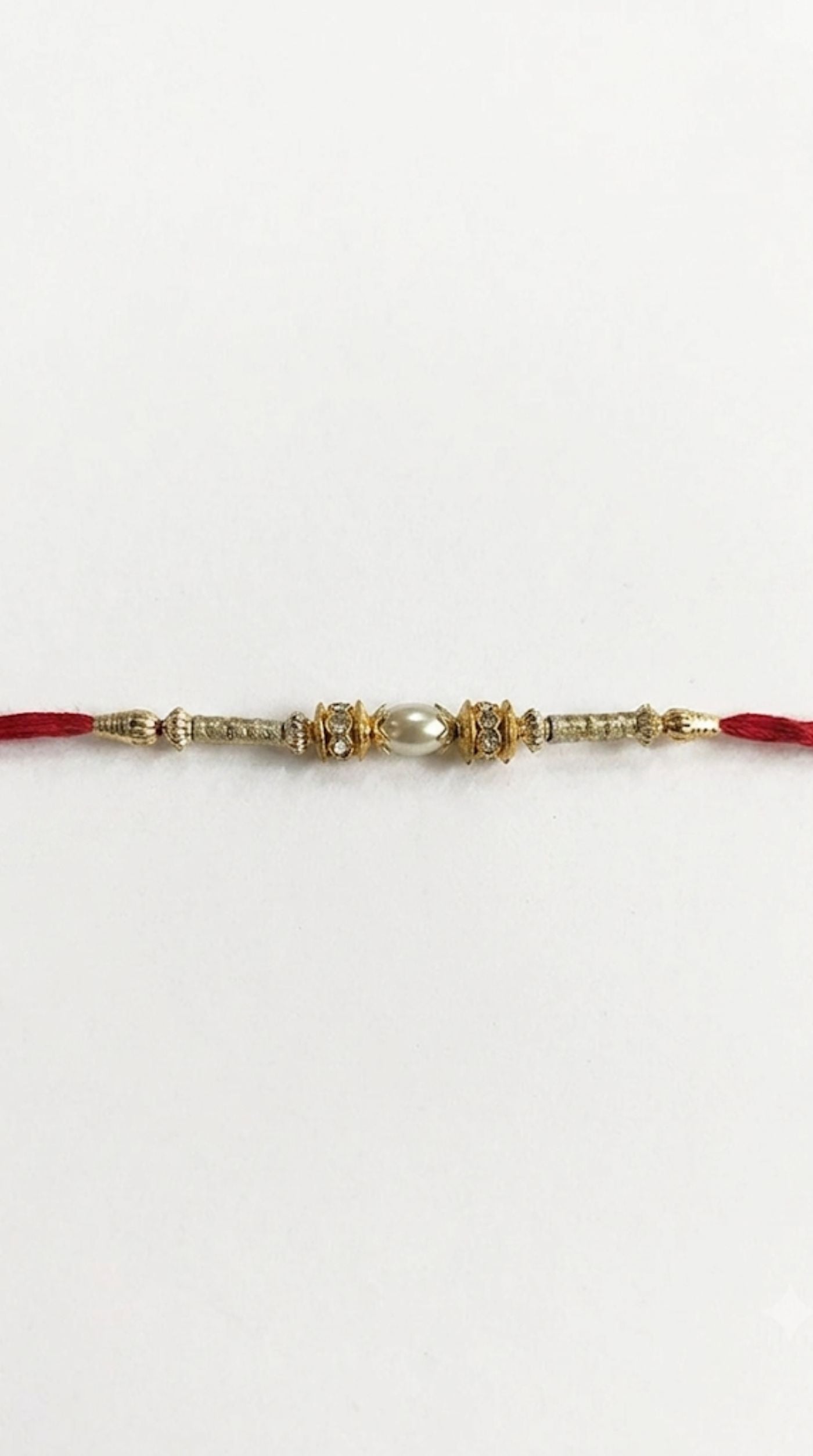 Close-up of light gold Rakhi with pearl centrepiece