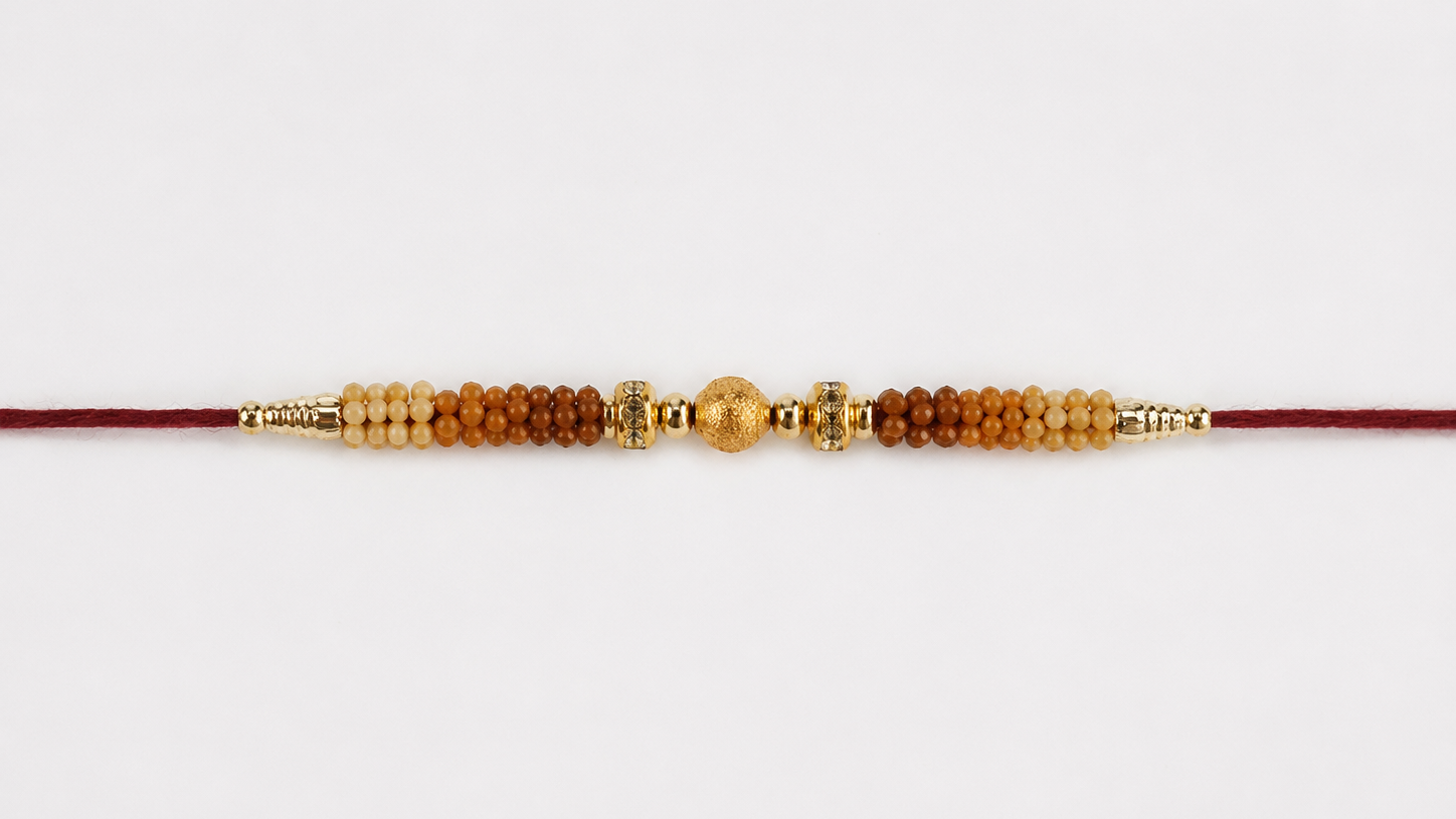 A traditional Indian Rakhi beaded cord bracelet with red thread, brown wooden beads, and gold-toned metal spacers.