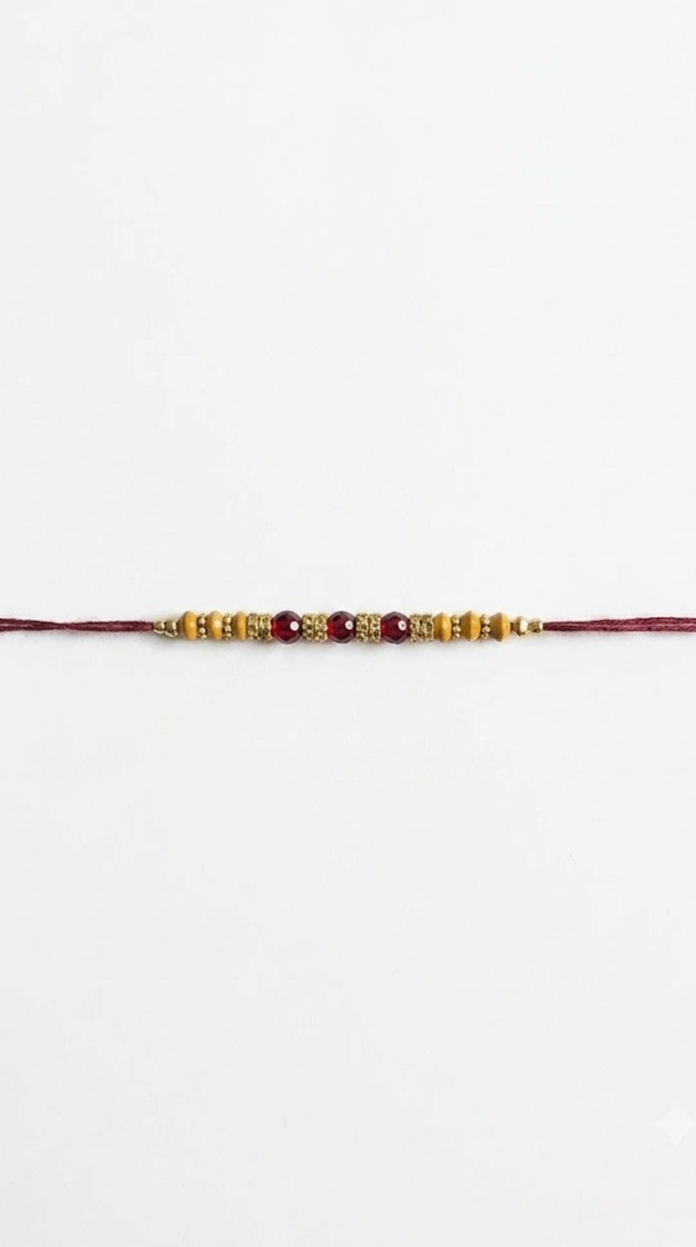 Close-up of wood and bead Rakhi with maroon bead detailing