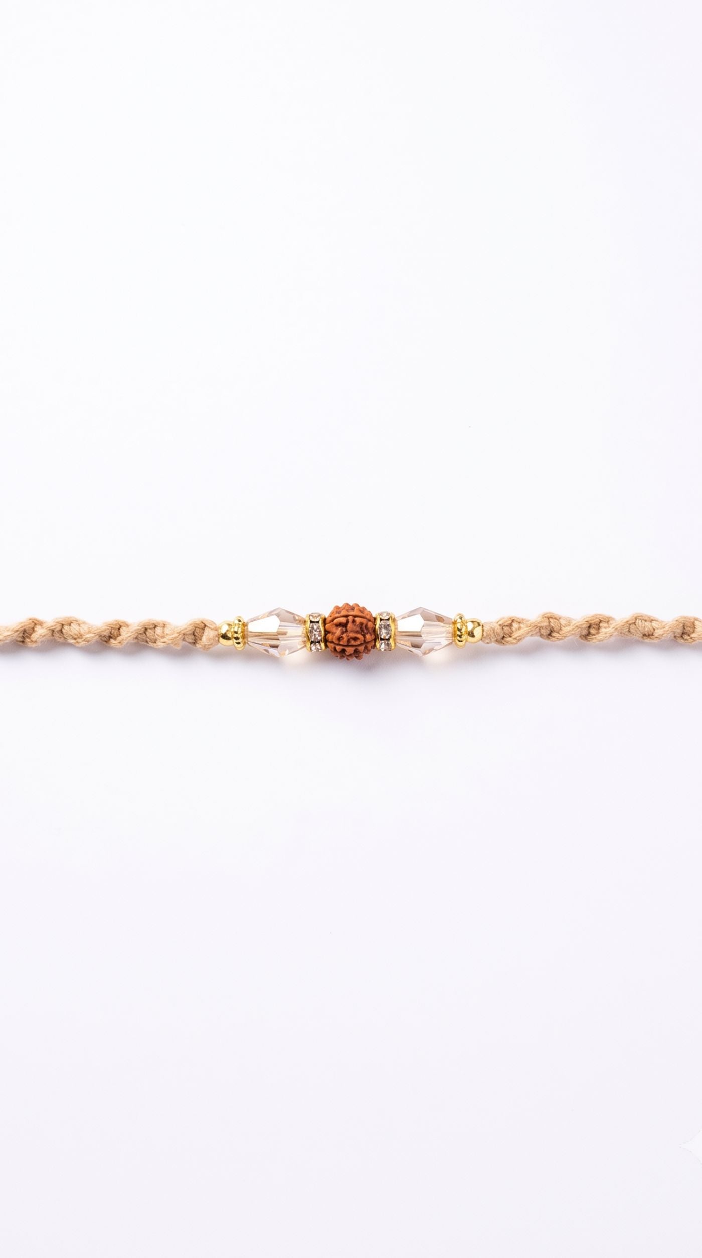 Rudraksha rakhi with clear crystal beads, gold-tone spacers, and beige braided thread worn on a man's wrist – Diya Online