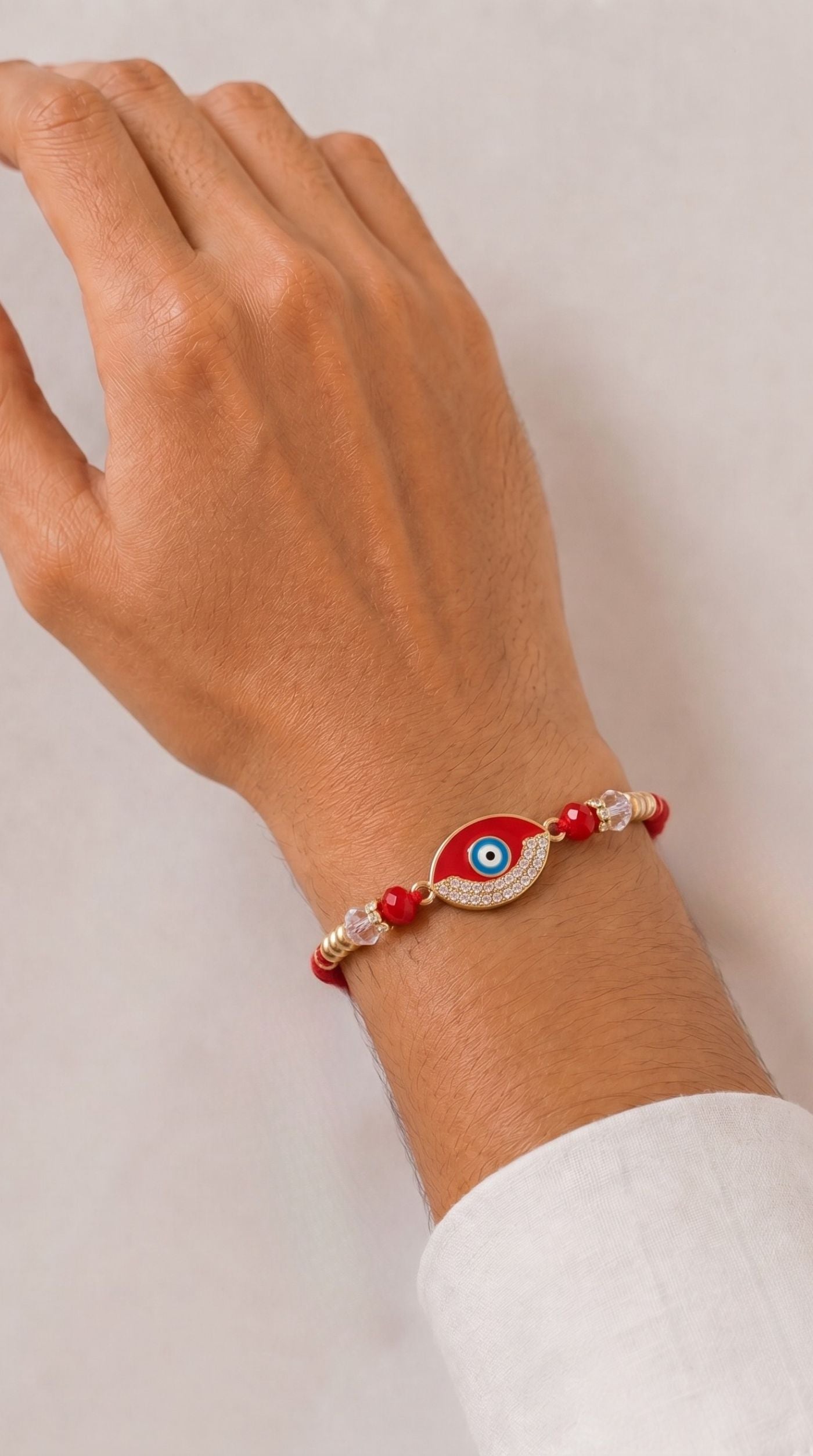 Red evil eye rakhi bracelet with crystal detailing, red beads, and adjustable red thread worn on a man's wrist – Diya Online