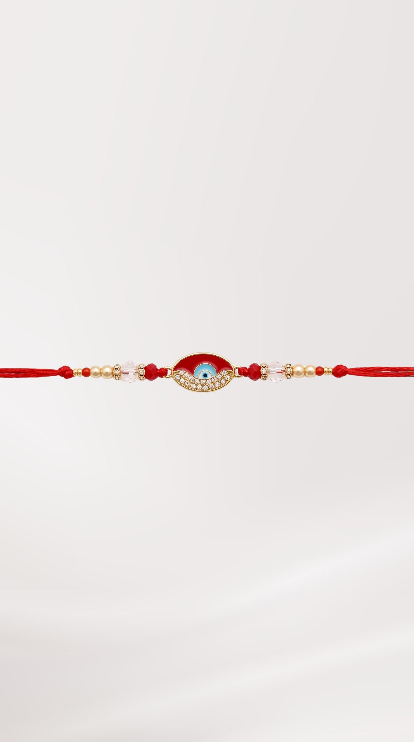 Red evil eye rakhi bracelet with crystal detailing, red beads, and adjustable red thread worn on a man's wrist – Diya Online
