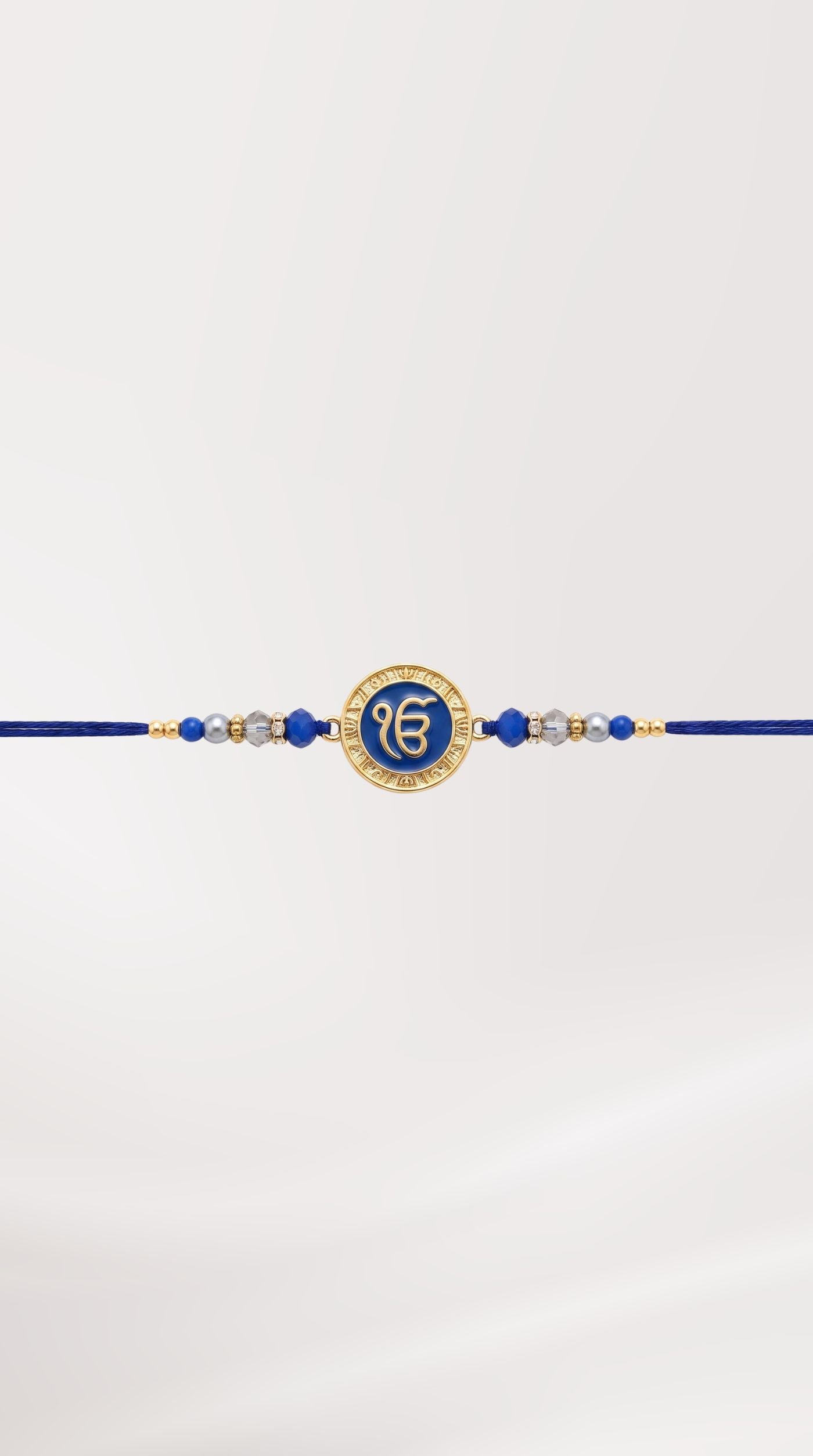 Blue Ek Onkar rakhi bracelet with crystal-studded centerpiece, blue crystal beads, silver-tone spacers, and adjustable navy thread worn on a man's wrist – Diya Online