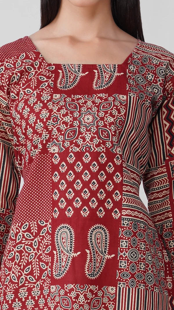 A close-up of a red long-sleeve kurta featuring a patchwork design of various paisley, floral, and geometric block prints in white and black.