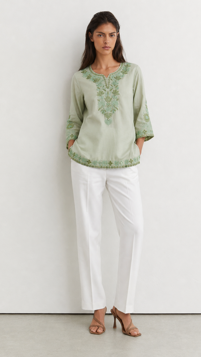 Young woman wearing a sage green embroidered kurta top with tonal floral threadwork, three-quarter sleeves and white trousers.