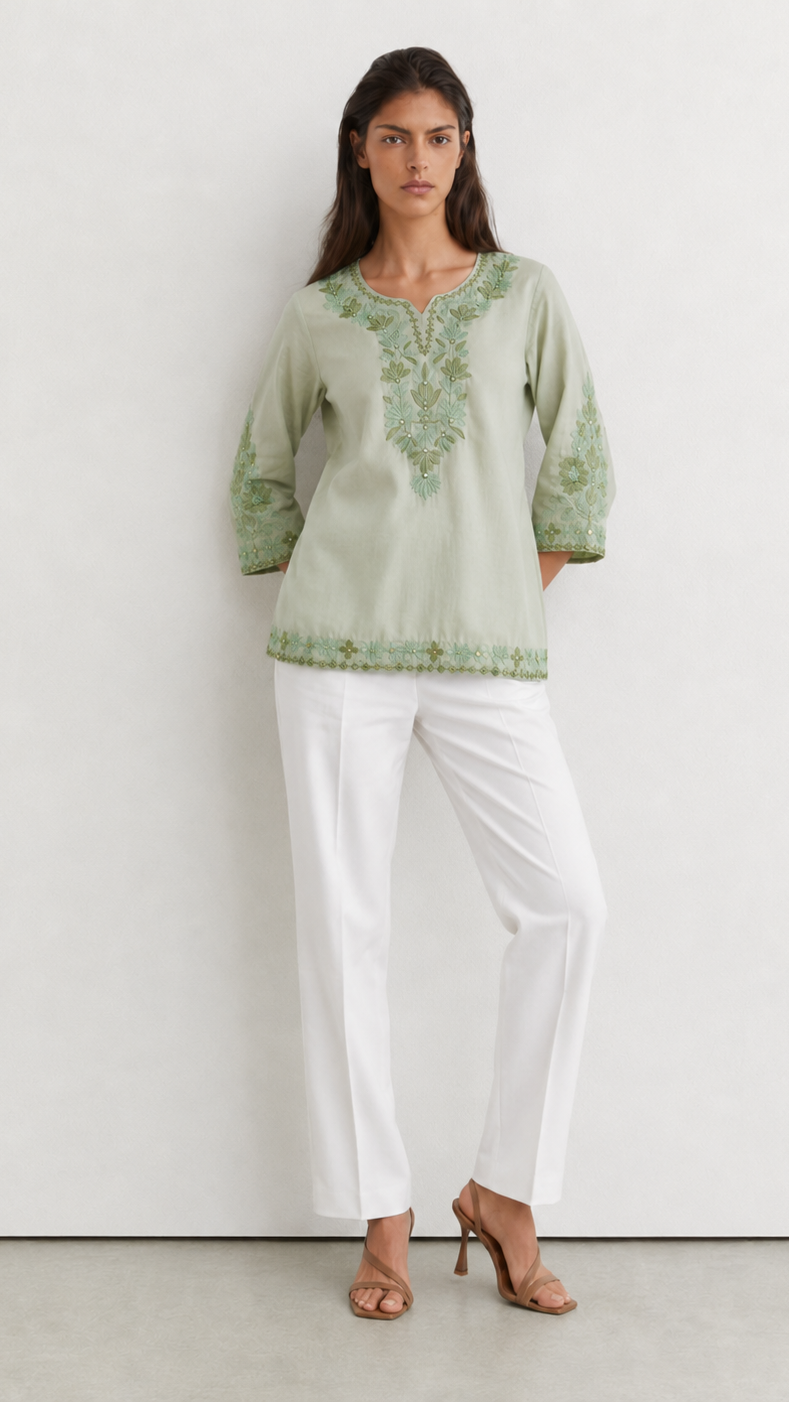 Young woman wearing a sage green embroidered kurta top with tonal floral threadwork, three-quarter sleeves and white trousers.