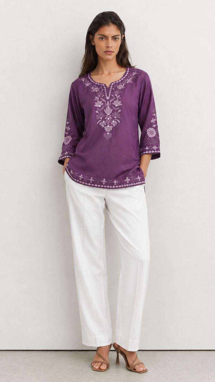 Young woman wearing a purple embroidered kurta top with tonal floral threadwork, three-quarter sleeves and white trousers.