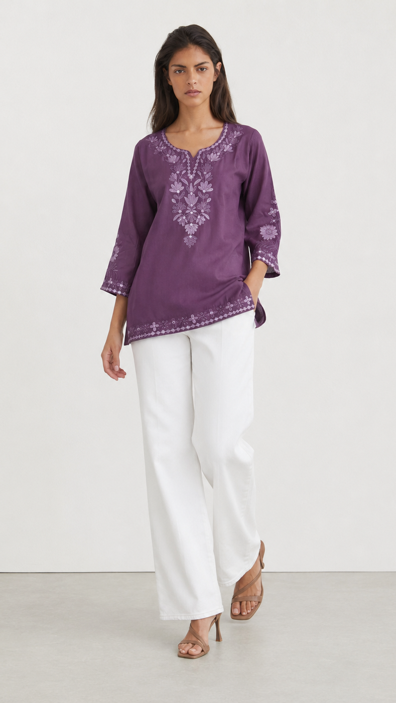 Young woman wearing a purple embroidered kurta top with tonal floral threadwork, three-quarter sleeves and white trousers.