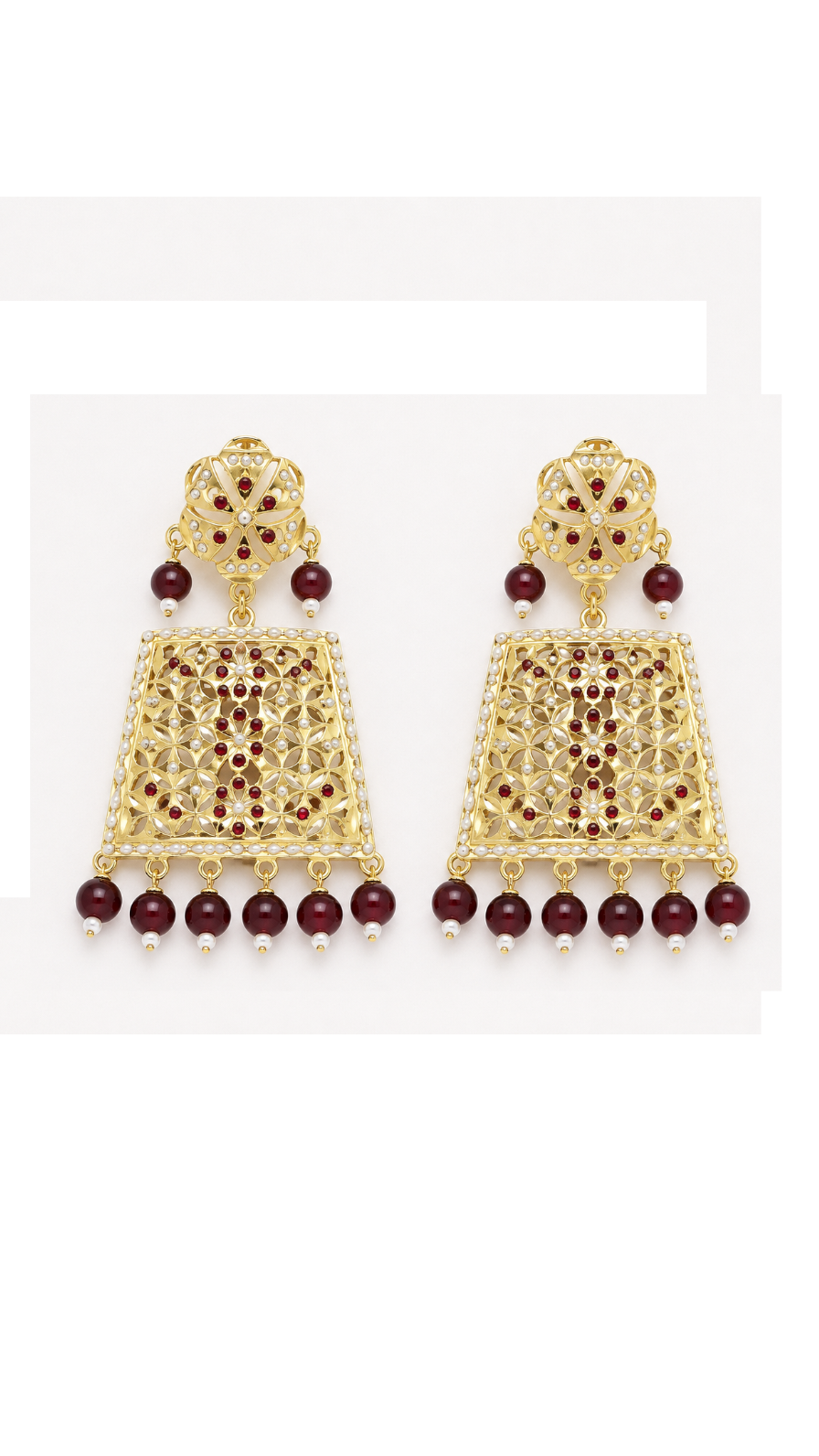A pair of gold-toned traditional Indian jhumka earrings with deep red stones and dangling maroon beads.