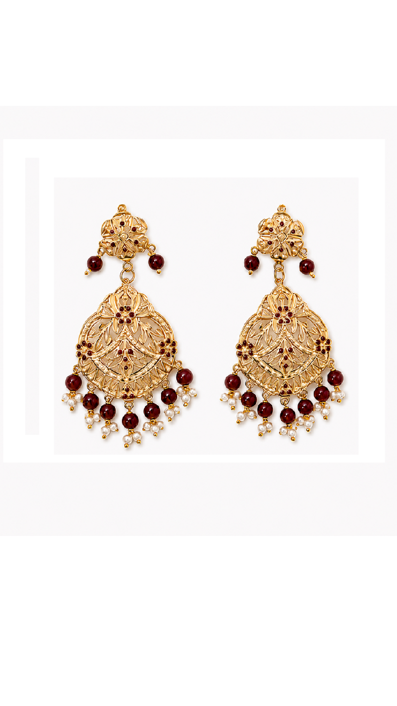 A pair of ornate gold-toned jadau dangle earrings with red gemstone accents and small pearl-like beads.