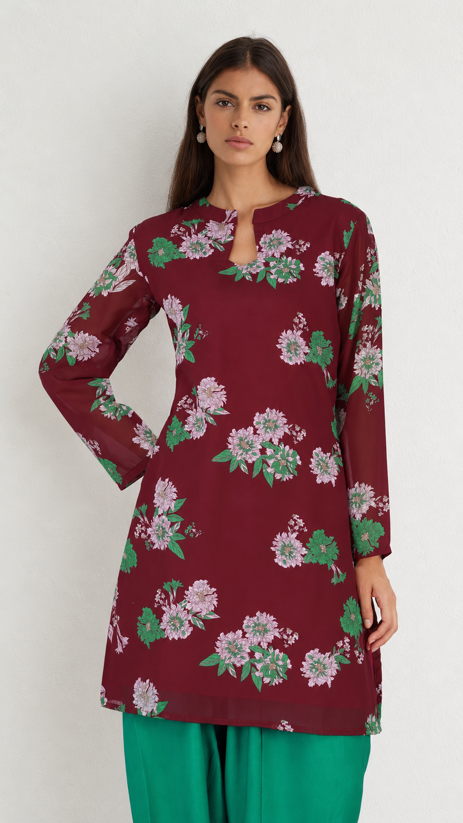 A woman modeling a long-sleeve maroon kurta with a green and pink floral print, paired with green pants, against a plain light gray background.