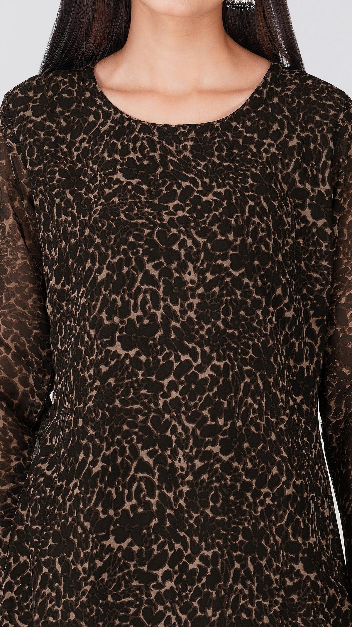 A close-up of a woman wearing a long-sleeve top with a brown and black leopard print pattern.