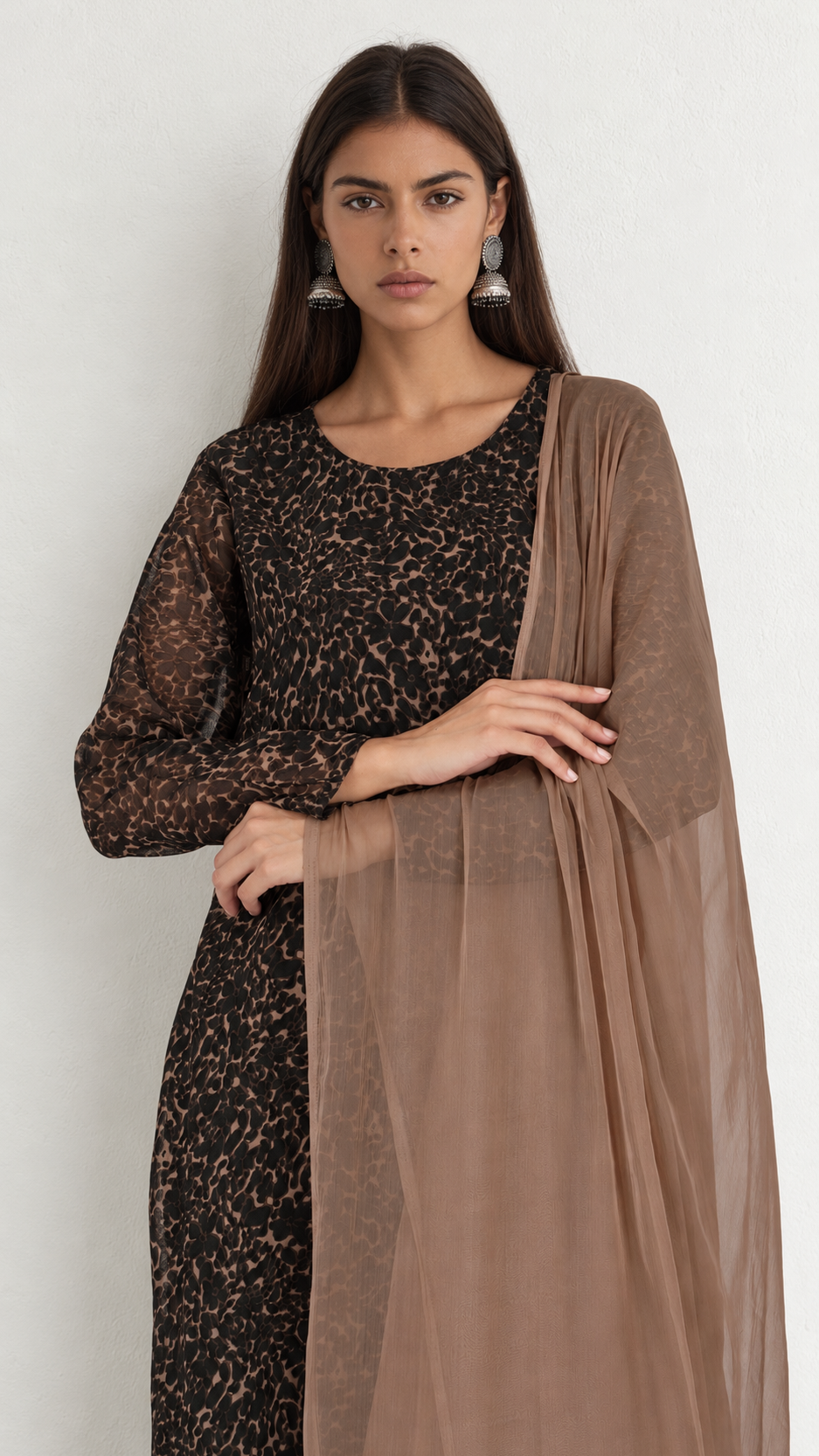 A woman modeling a traditional three-piece outfit featuring a black and brown patterned kurta, a solid black dupatta, and a sheer brown organza dupatta draped over her shoulder, set against a plain light gray background.