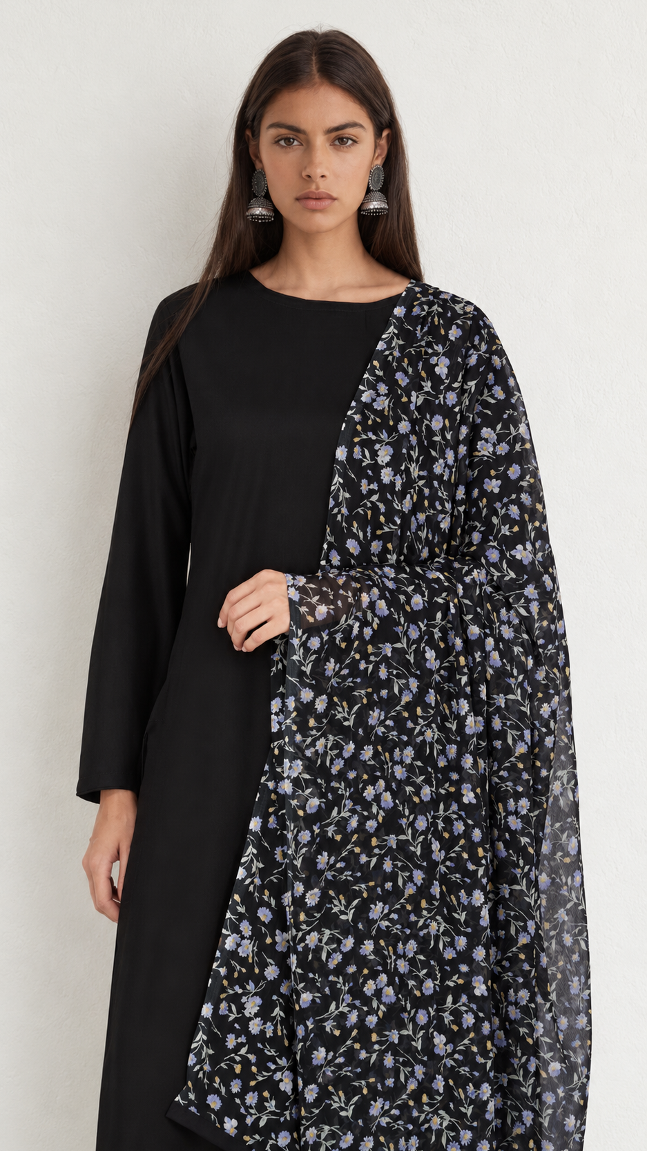 A woman modeling a black long-sleeve kurta paired with a black dupatta featuring a light purple and white floral pattern, set against a plain light gray background.