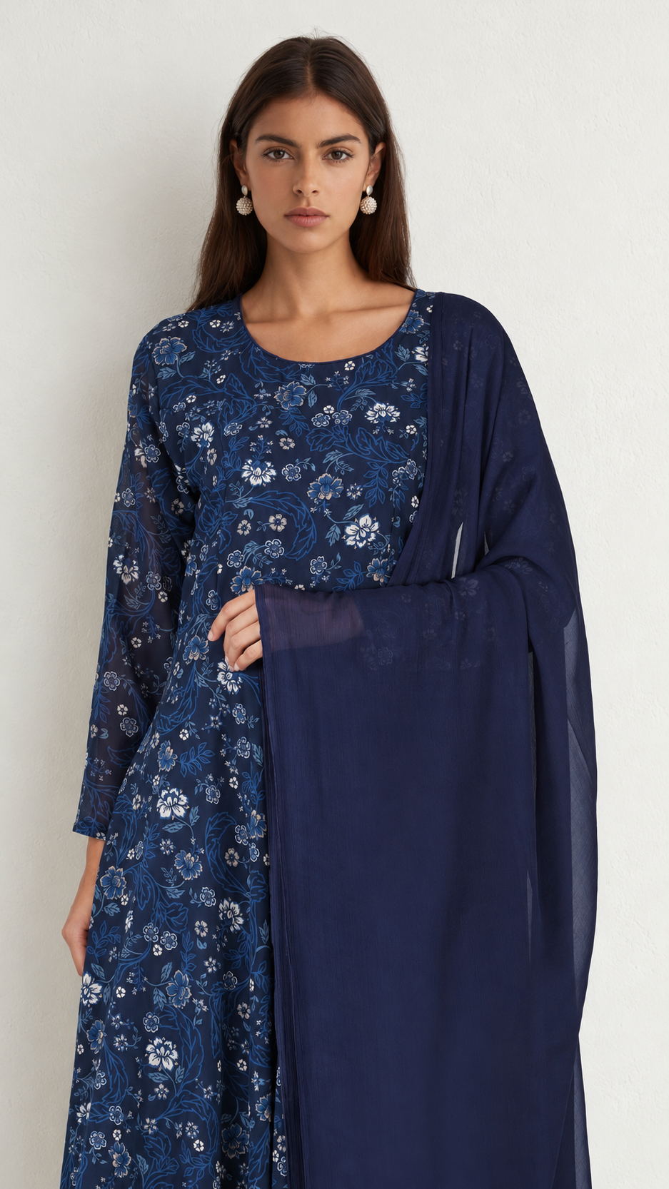 A woman modeling a navy blue long kurta with white floral embroidery and a matching sheer navy dupatta, set against a plain off-white background.