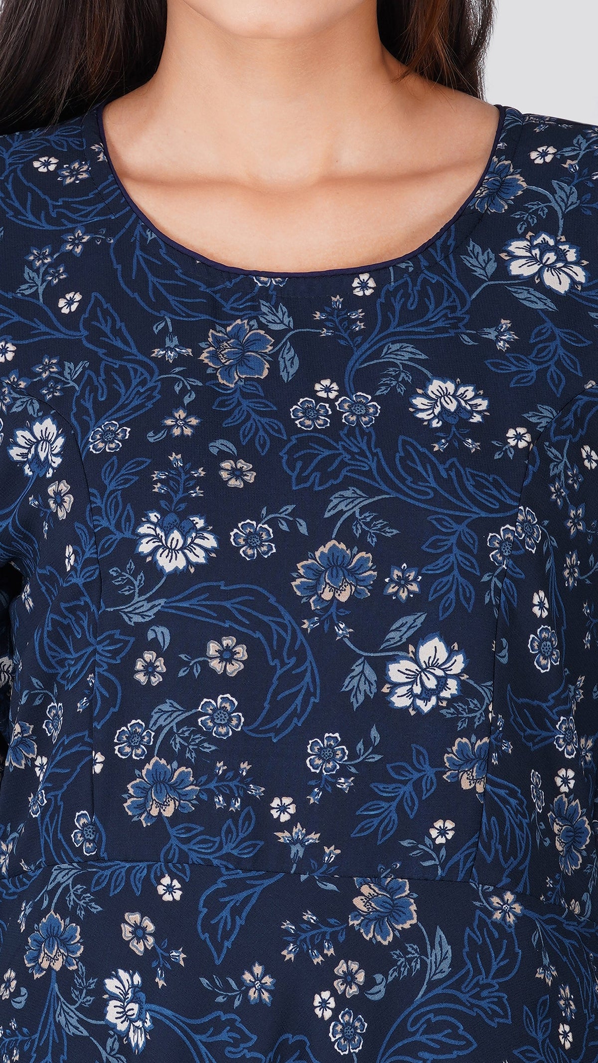 A close-up of a woman wearing a navy blue top with a detailed blue and white floral pattern.