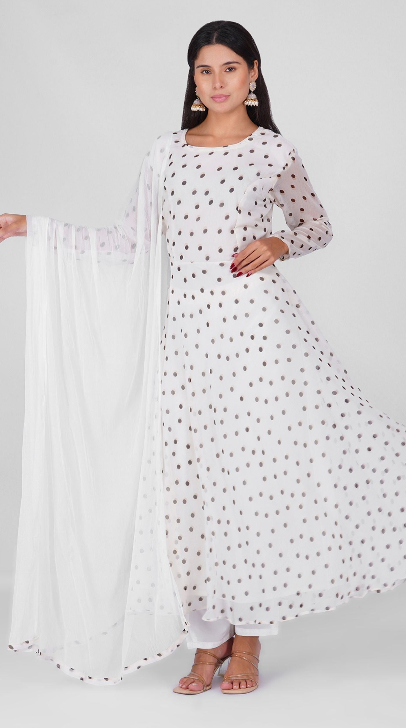 Woman wearing a white georgette bias cut suit set with black polka dot print, white crepe trousers, and printed chiffon dupatta – Diya Online