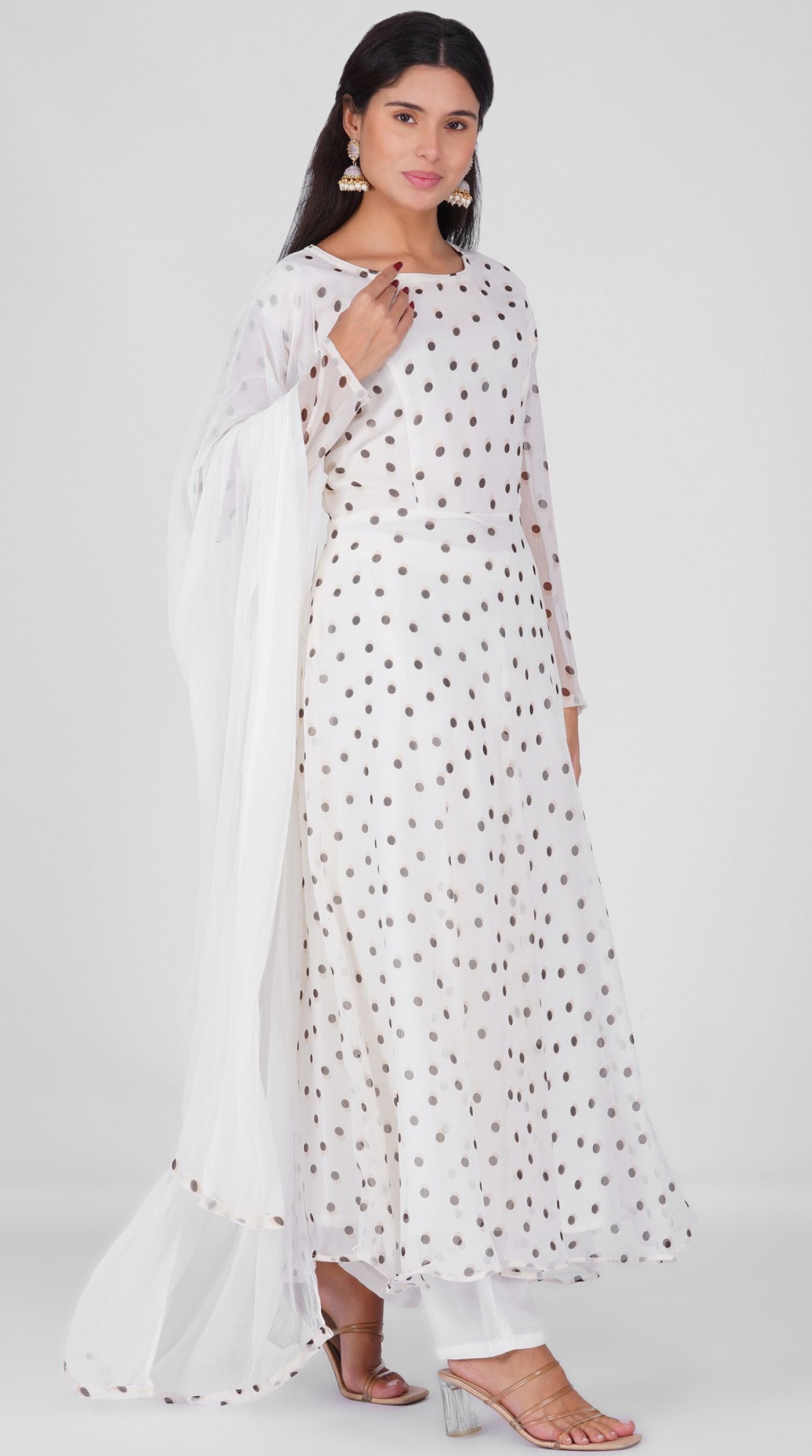 Woman wearing a white georgette bias cut suit set with black polka dot print, white crepe trousers, and printed chiffon dupatta – Diya Online