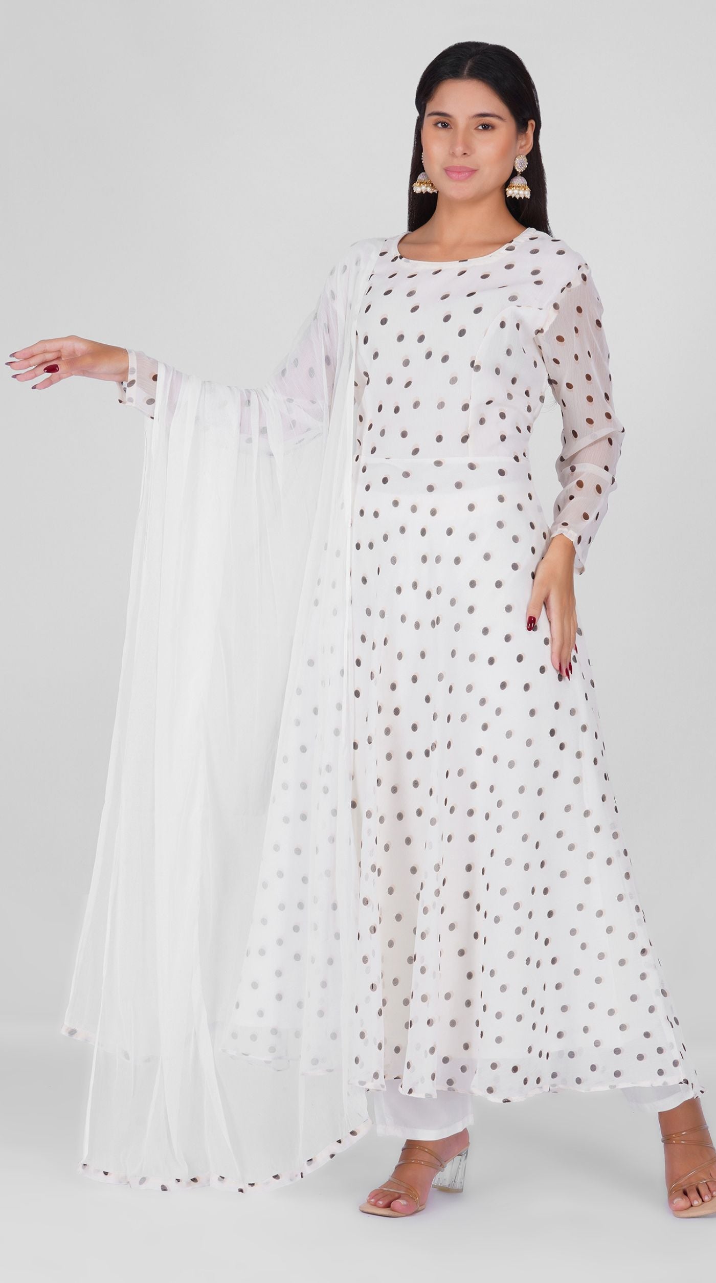 Woman wearing a white georgette bias cut suit set with black polka dot print, white crepe trousers, and printed chiffon dupatta – Diya Online