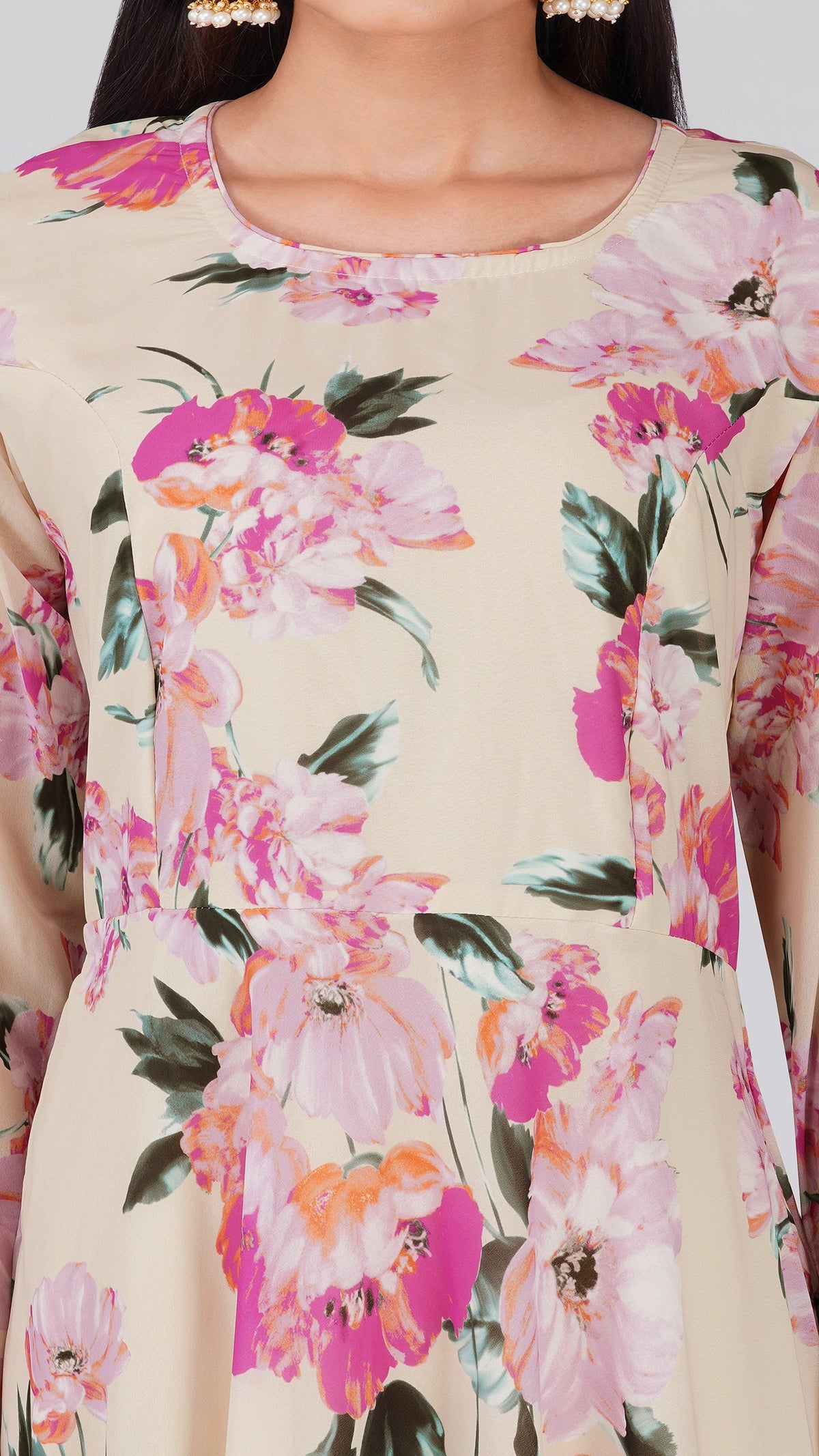 A close-up of a woman wearing a beige long-sleeve kurta with a vibrant pink, orange, and green floral print.