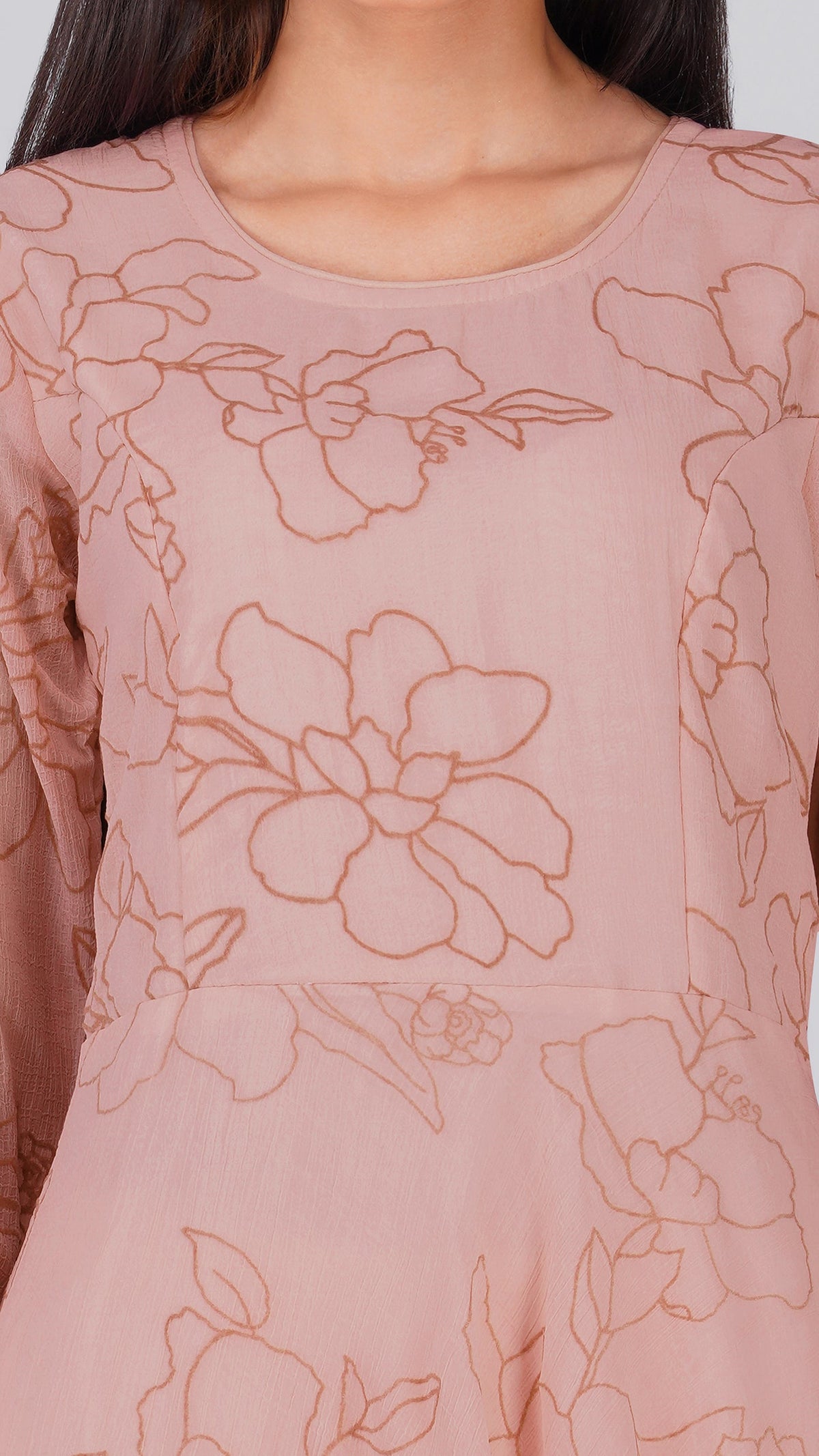 A close-up of a dusty pink long-sleeve top with a tonal brown floral line-art print, shown on a model.