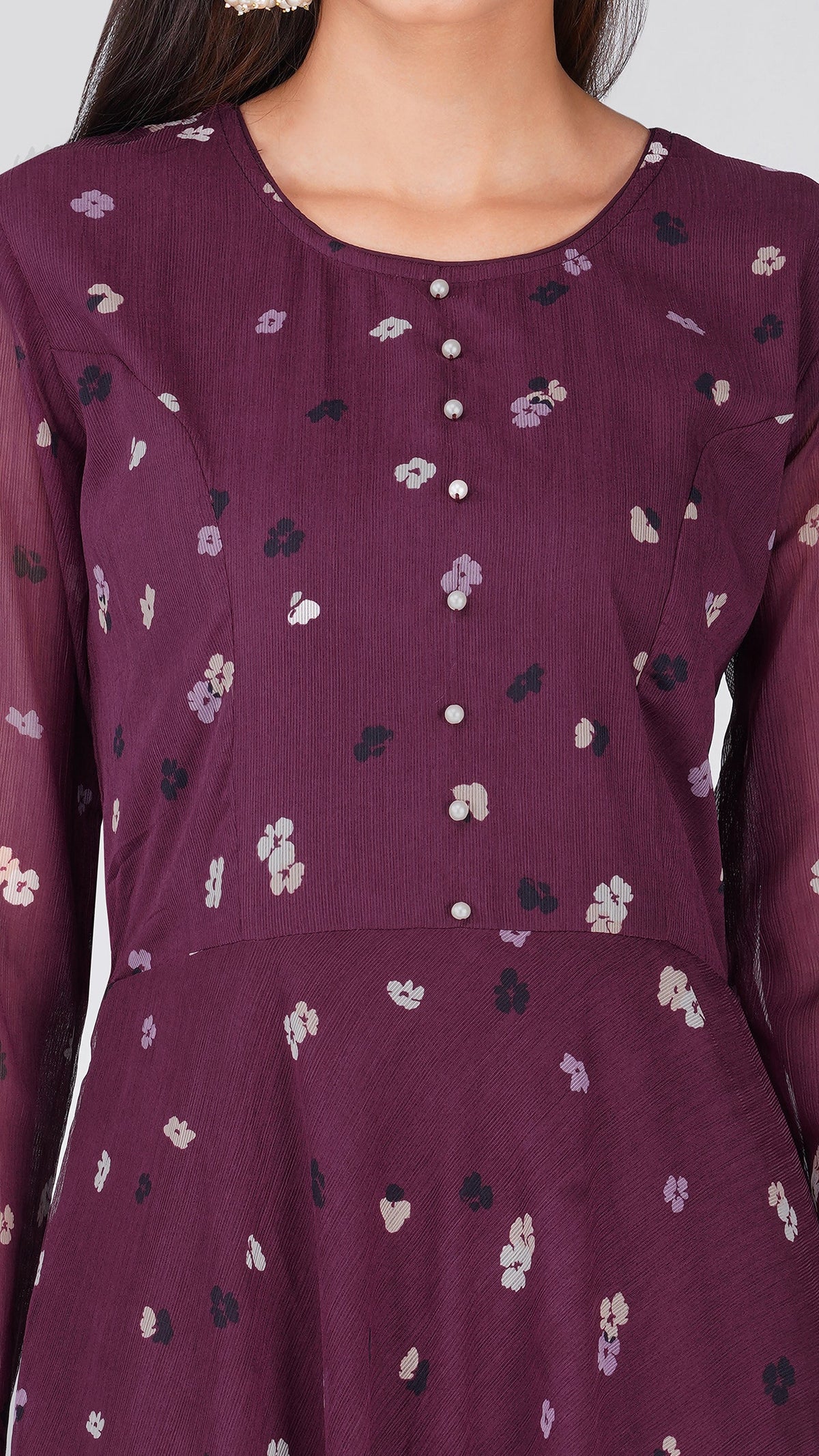 A close-up of a woman wearing a long-sleeve purple kurta with a small floral pattern and a buttoned neckline.