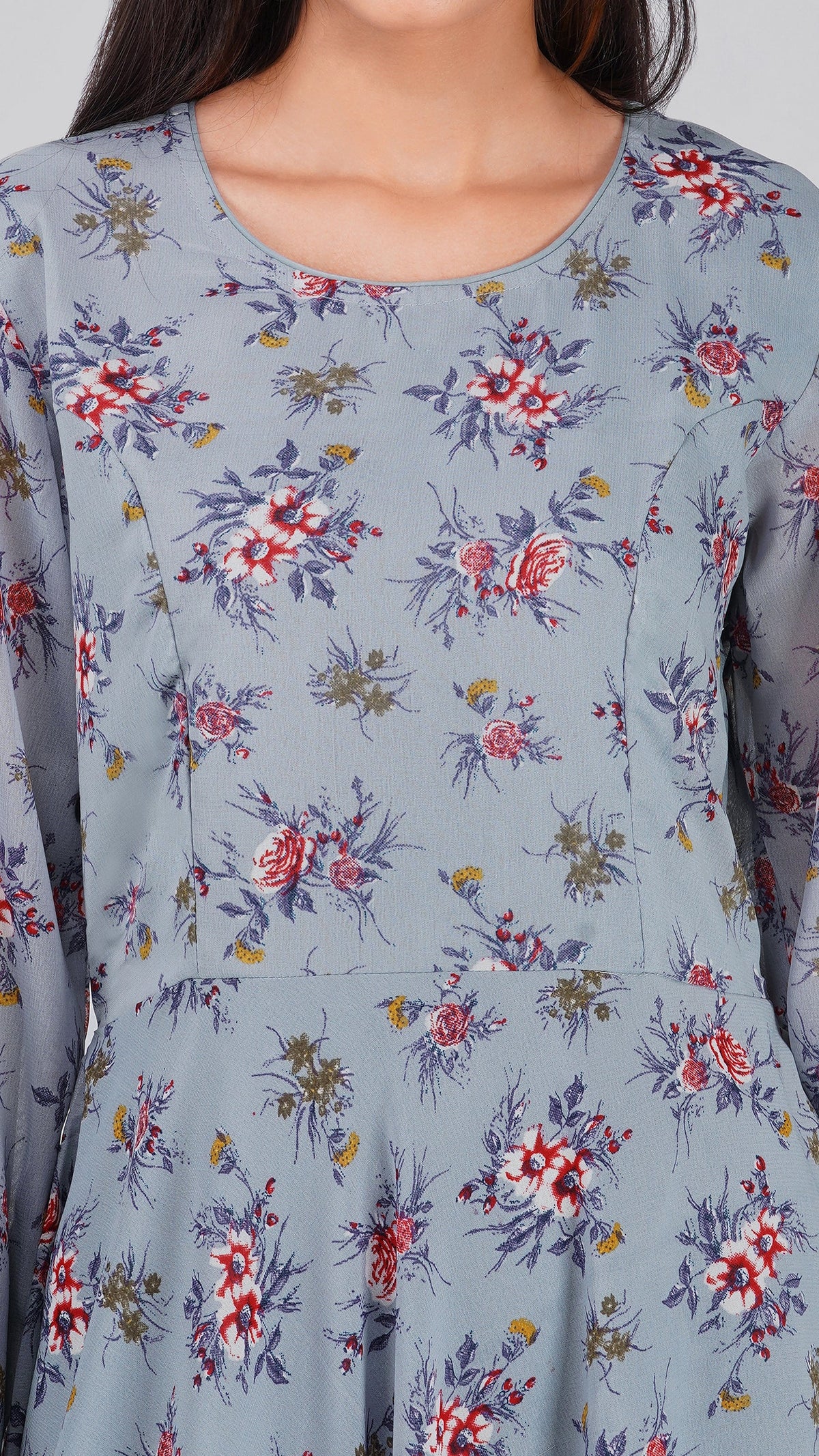 A close-up of a woman wearing a dusty blue long-sleeve dress with a red, purple, and yellow floral pattern.