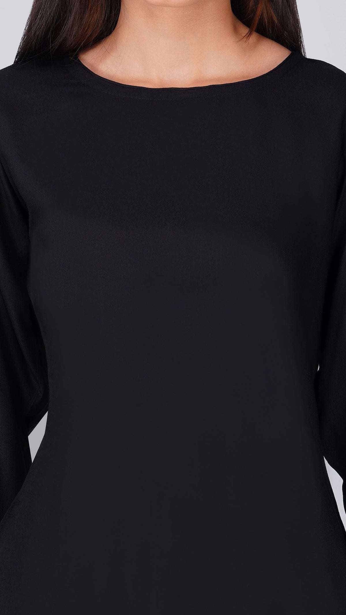 A close-up of a model wearing a solid black long-sleeve top with a wide boat neckline.