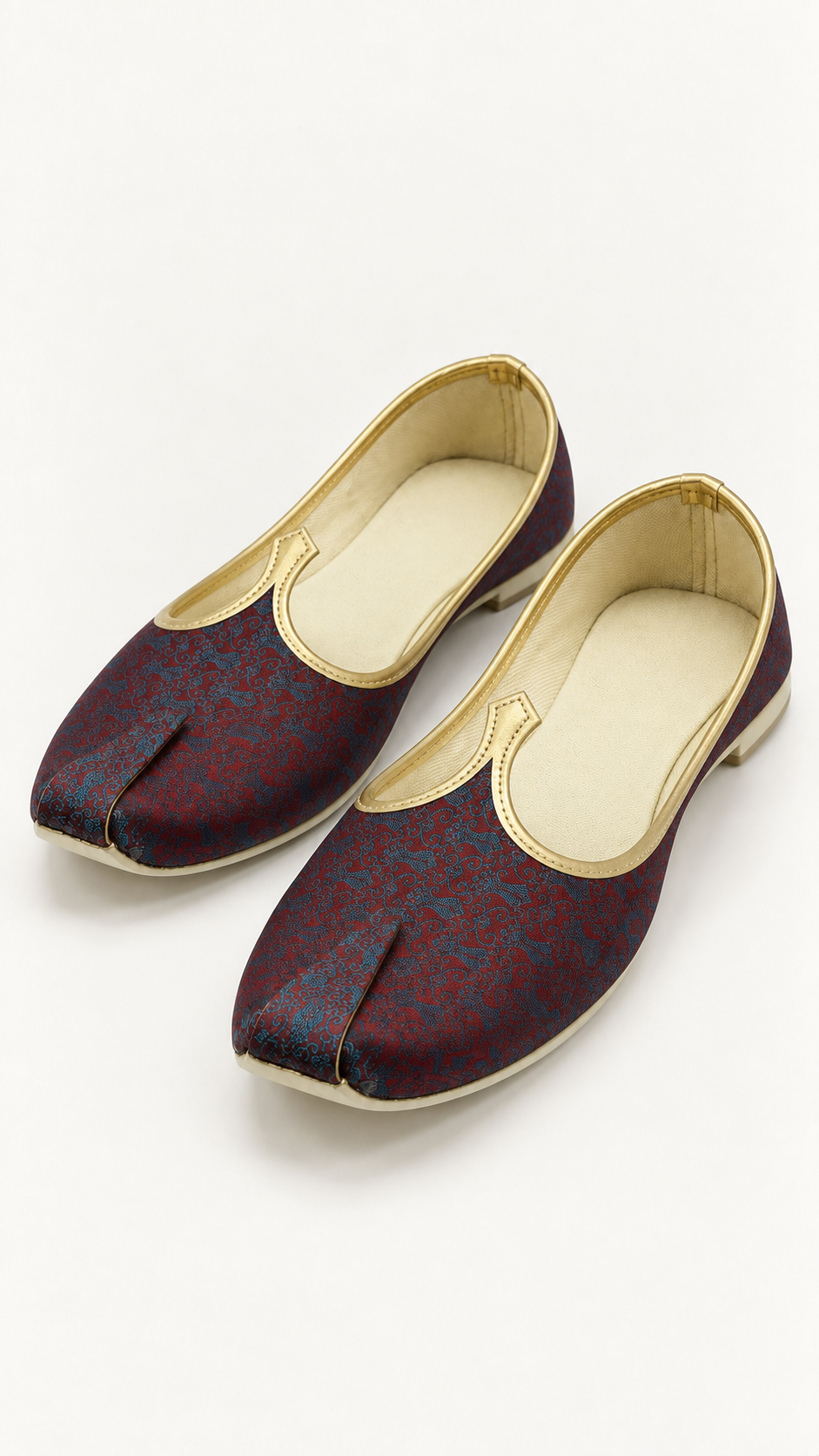 A pair of traditional Indian shoes in a deep maroon brocade fabric with gold trim and cream-colored insoles, displayed on a clean white background.